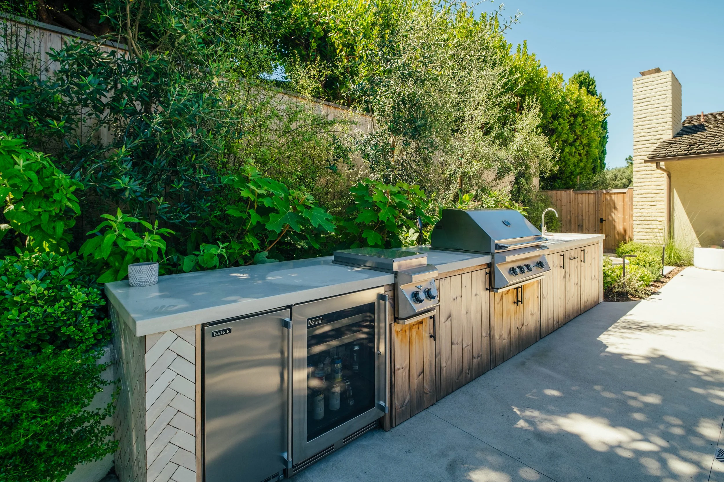 Custom outdoor kitchen with built-in barbecue by Rosewood Landscape