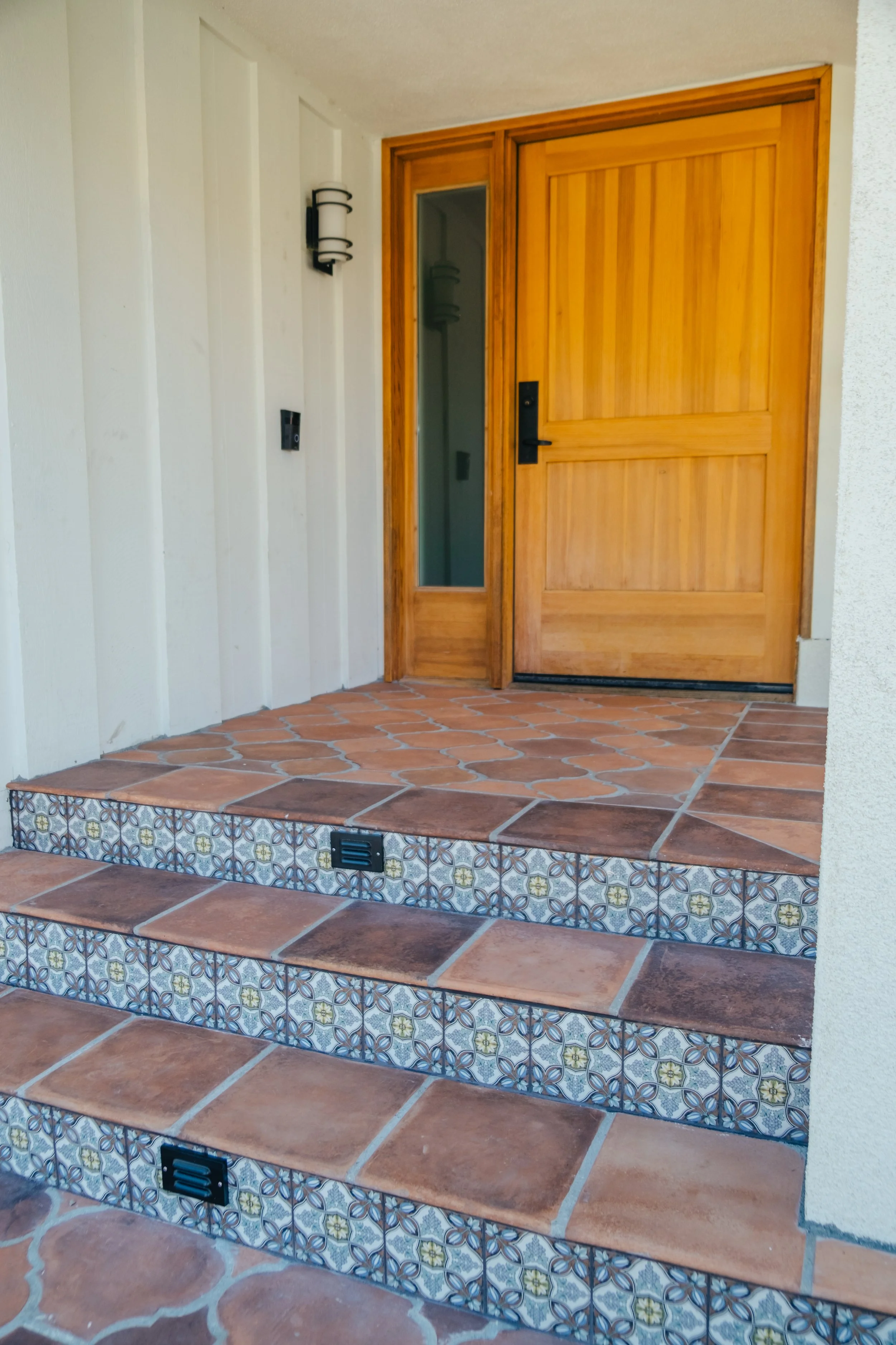 Spanish-style tiled entry steps with terracotta hardscape by Rosewood Landscape