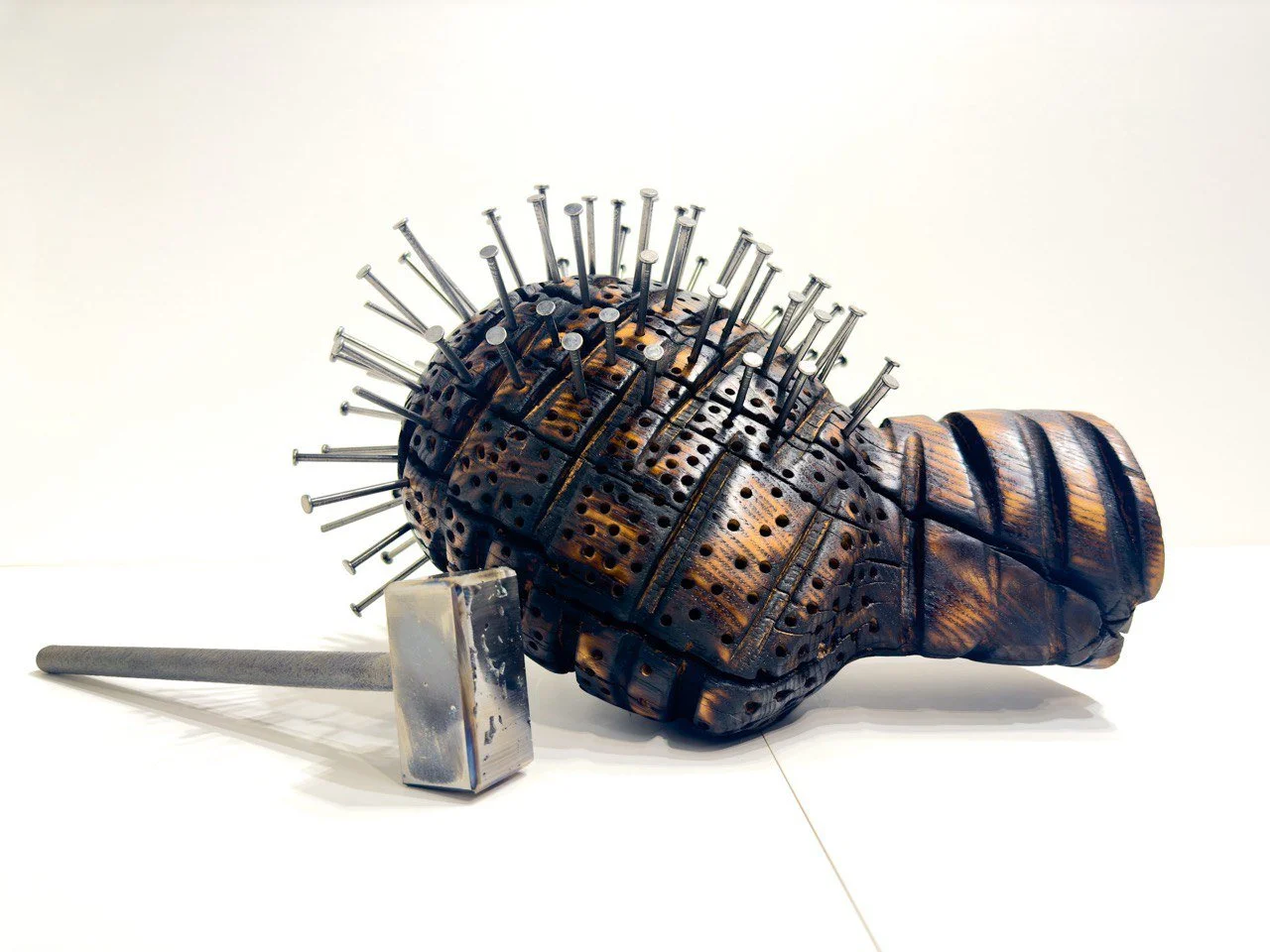 Scars, 2023,Wood & Metal, 8.5" × 10.5" × 16.5"

This piece features a wooden head devoid of facial features, accompanied by a metal hammer, creating a powerful visual metaphor for psychological distress, trauma, and the enduring impact of violence. D