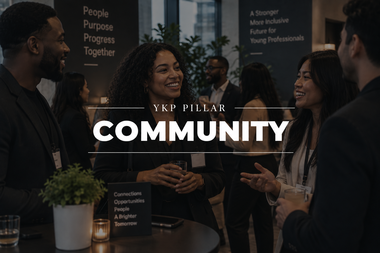 Group of diverse professionals socializing at a community event, smiling and talking, in a modern indoor setting with banners and plants in the background.