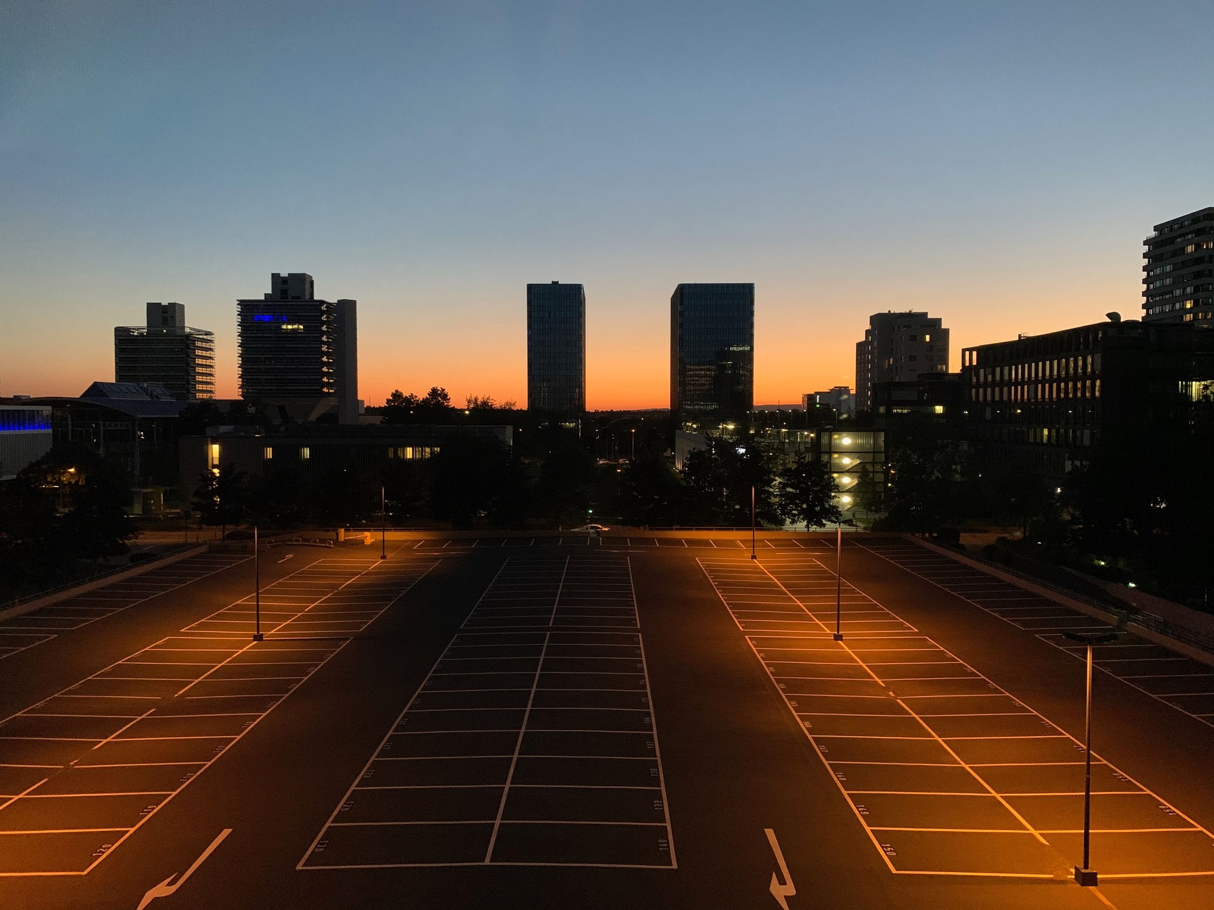 Empty parking lot at sunset with an urban city skyline in the background.