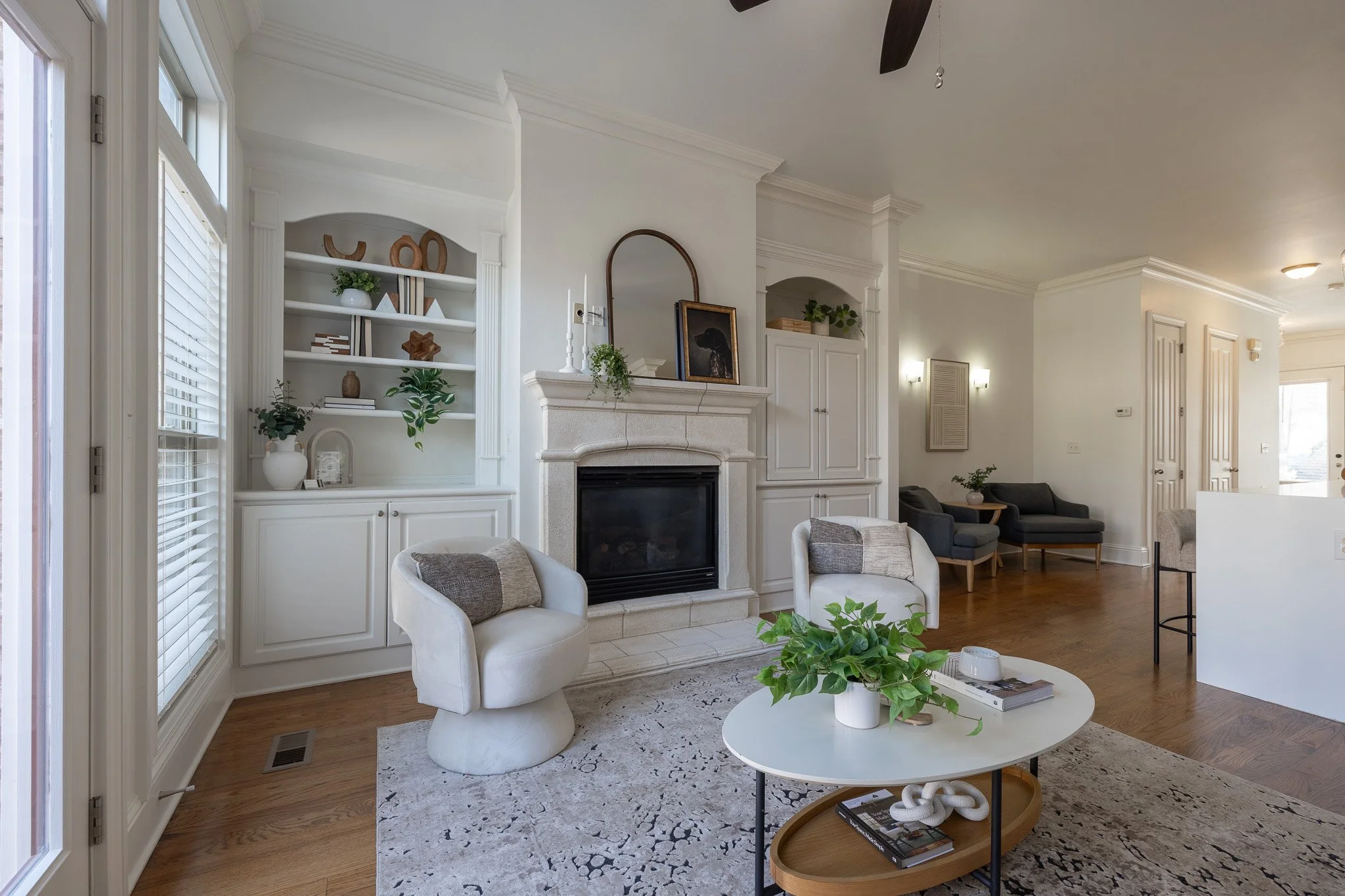 bright living room with a fireplace, built-in shelves, white swivel chairs and a round coffee table
