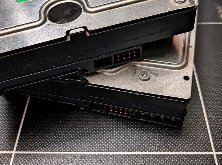 Two internal computer hard drives stacked on a black tiled surface.