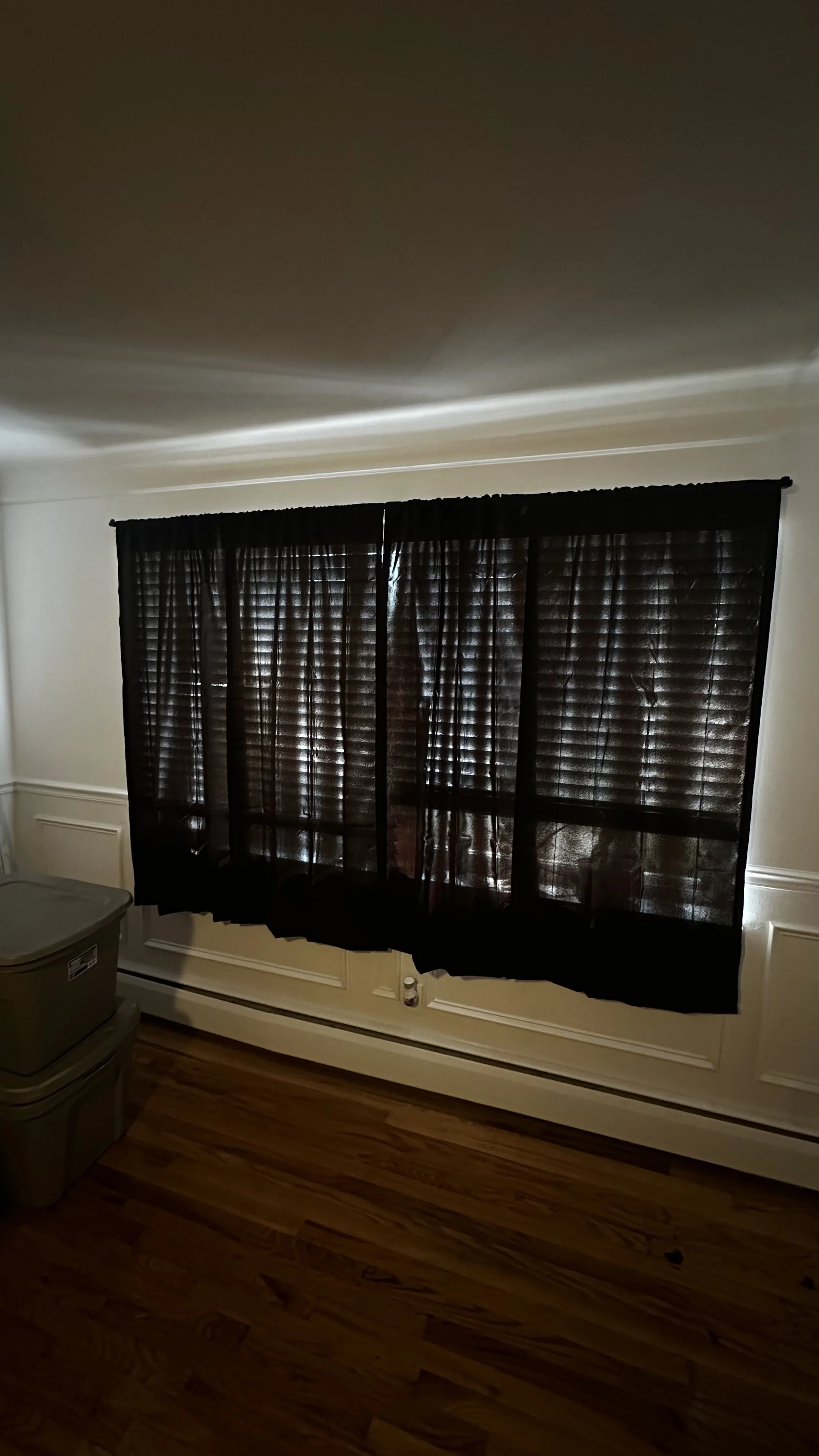 Black curtains installed over wooden blinds in a residential living room.