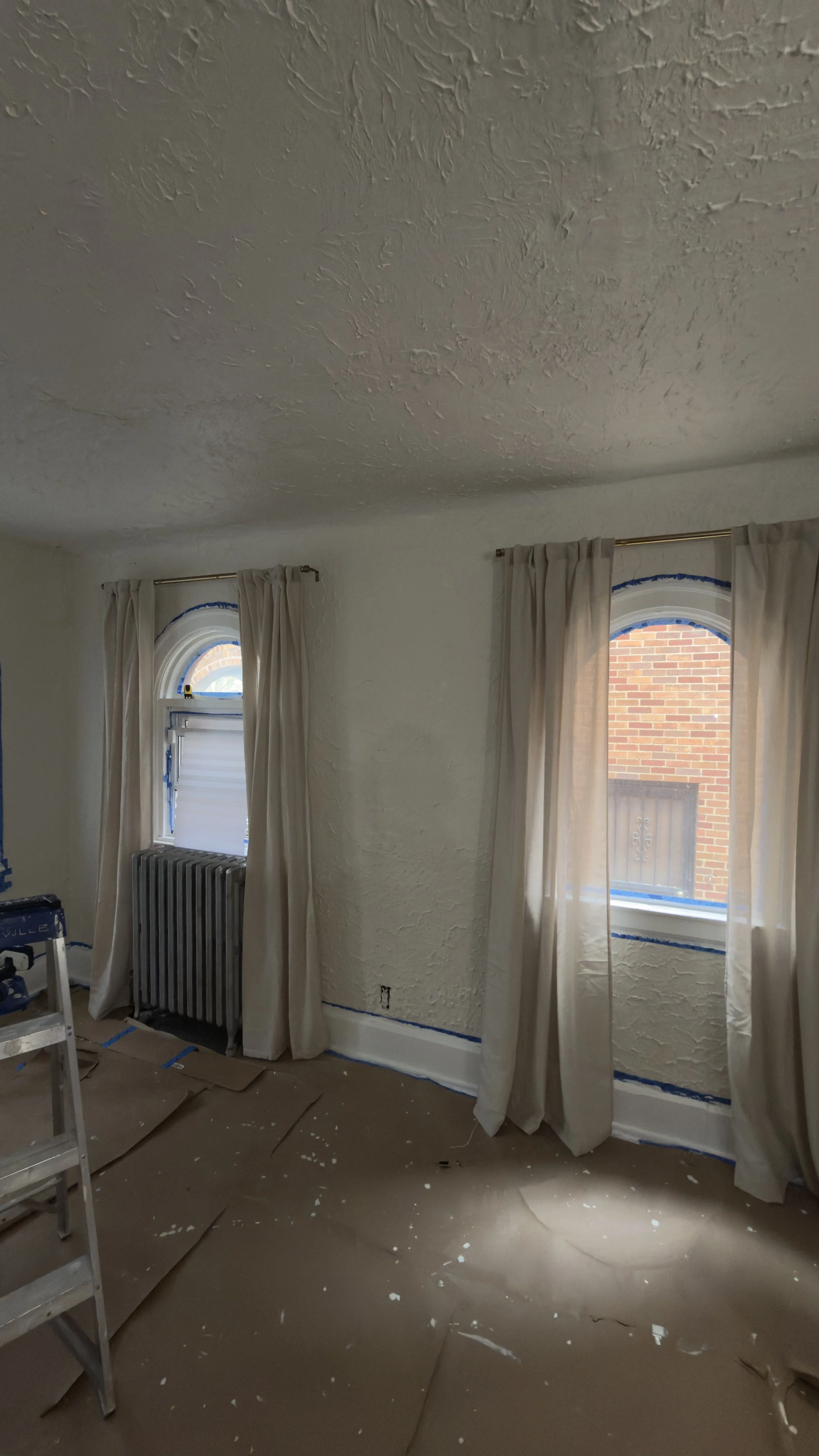 Residential room prepared for interior painting with trim and windows protected.