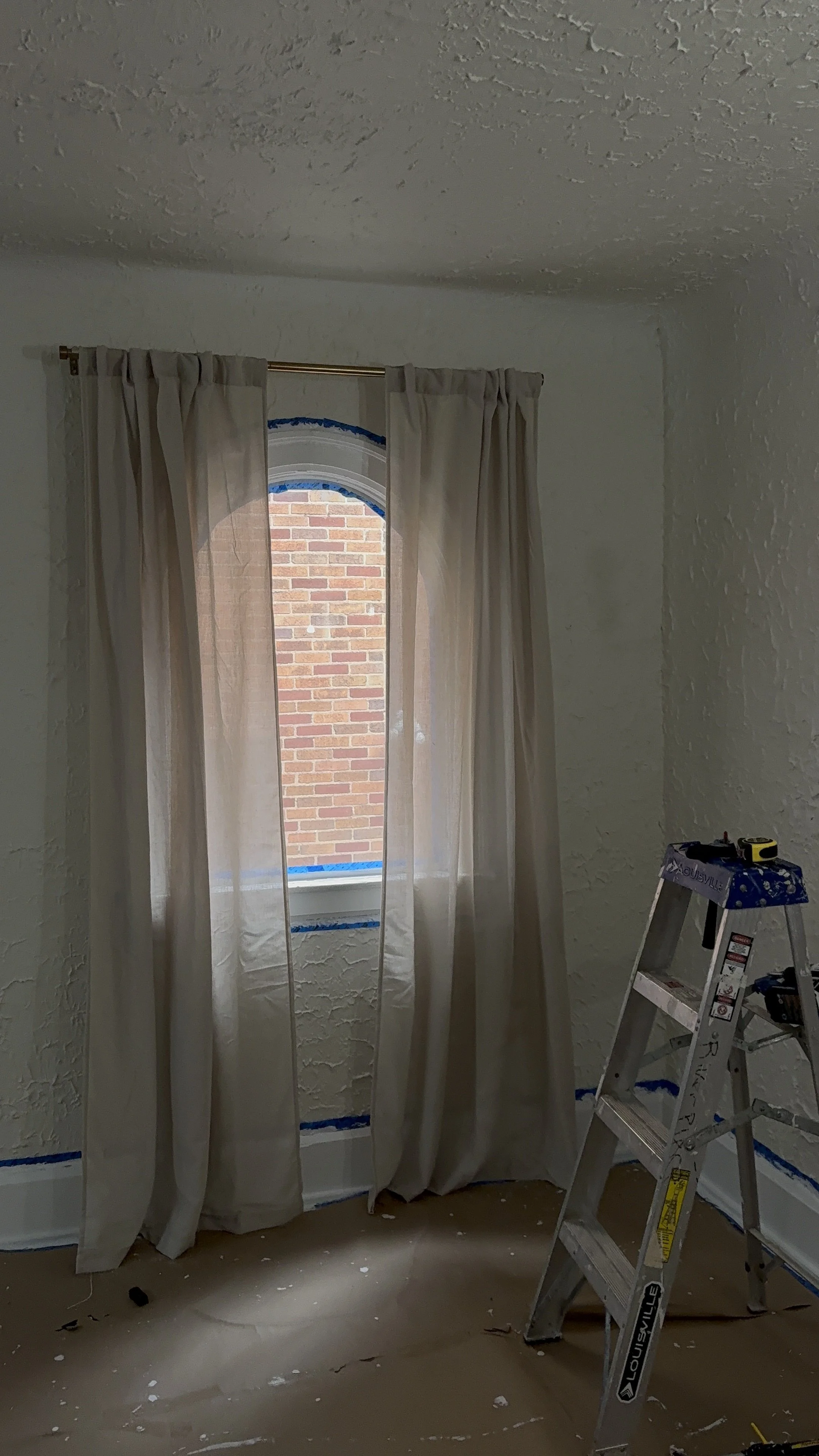 Beige curtains installed over a residential window during a home improvement project.