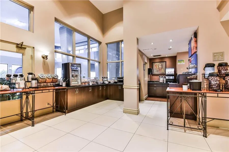 Coffee station with coffee dispensers, a coffee maker, and snack containers in a breakfast area.