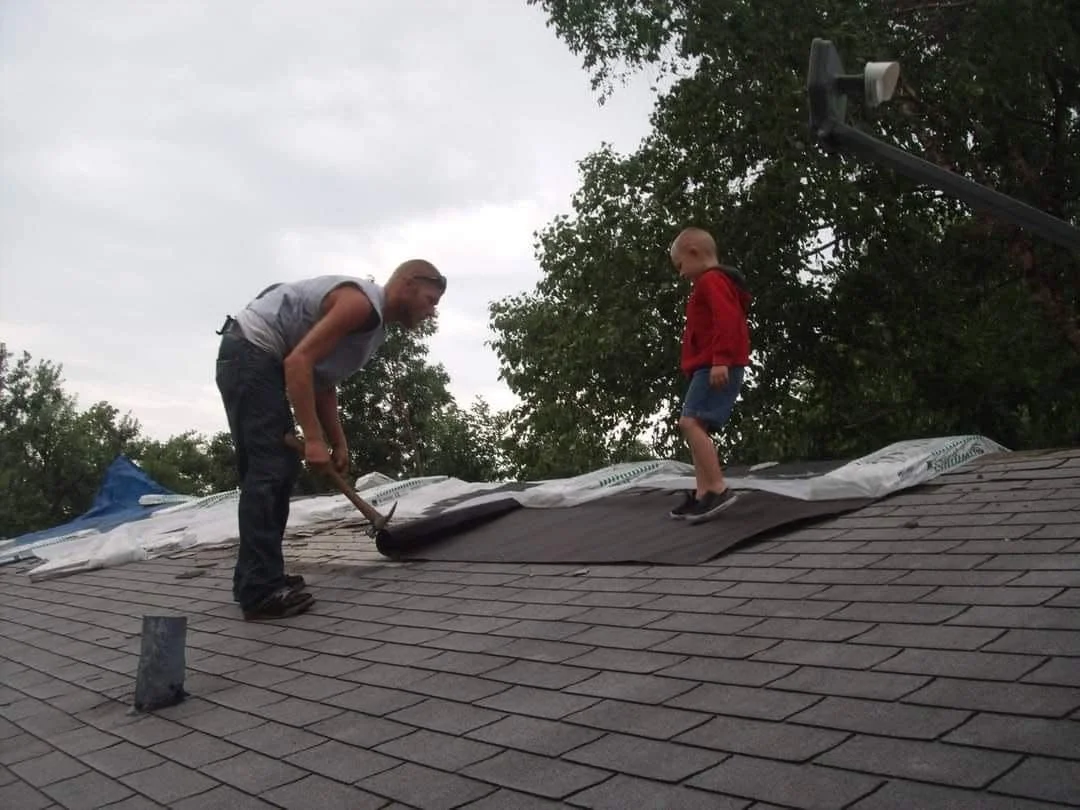 Travis and a young Aiden Sullivan reshingling a residential roof together in 2013