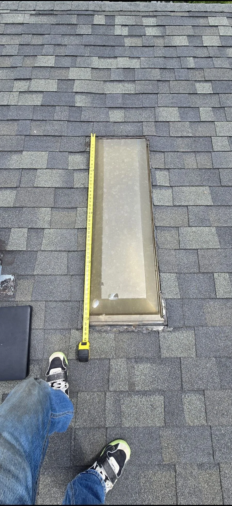 Before: an aging, hazy skylight being measured for replacement on a shingle roof
