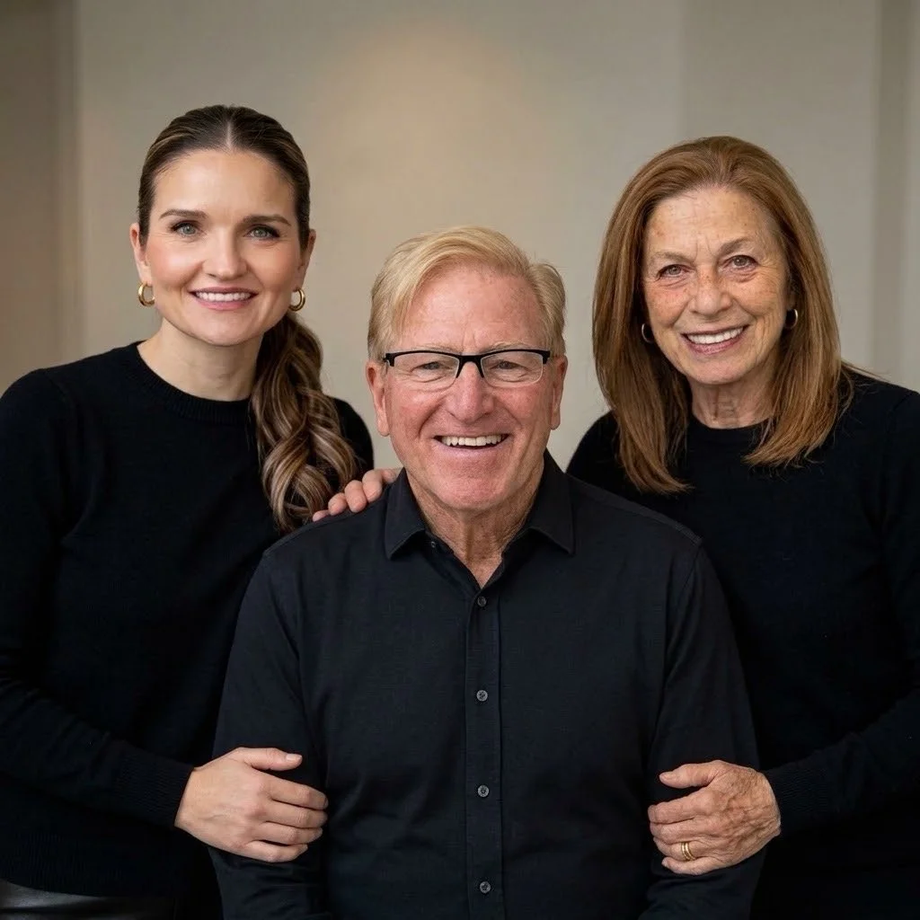 Three smiling people, two women and one man, posing closely together indoors.