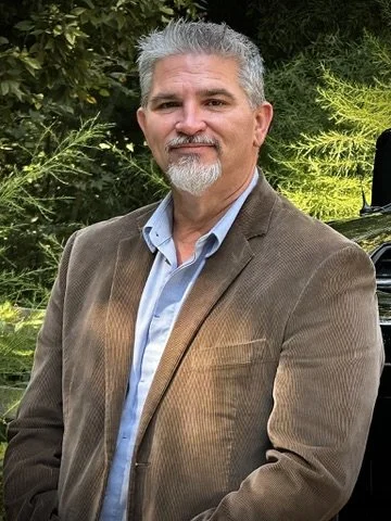 Daniel Henley in a brown blazer outdoors, professional portrait