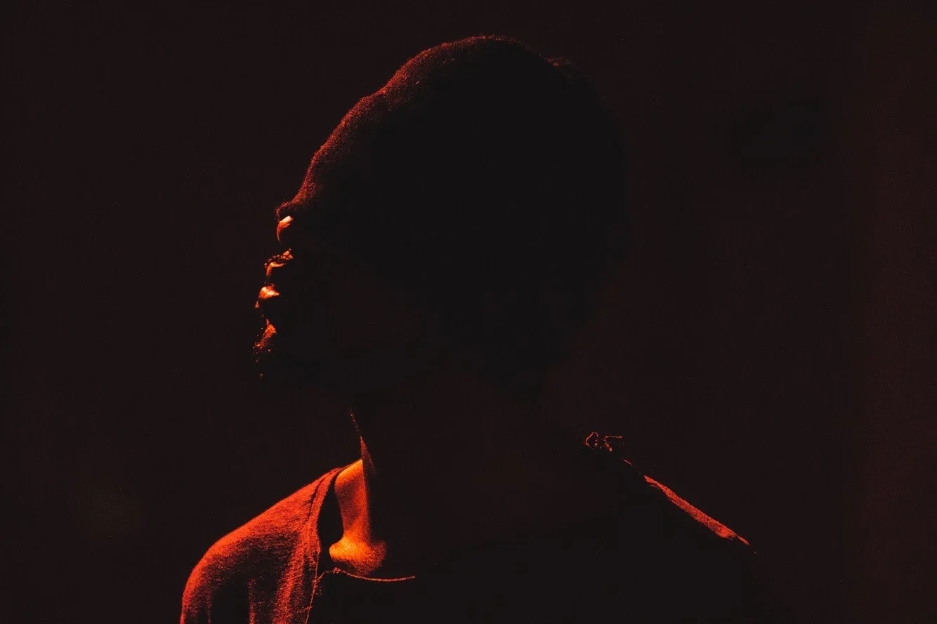 Silhouette of a person in dim lighting with reddish highlights, facing left