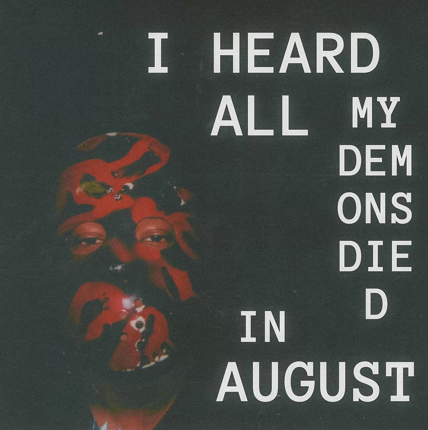 Close-up of text stating 'I HEARD ALL MY DEMONS IN AUGUST' on a dark background with a red abstract shape on the left side.