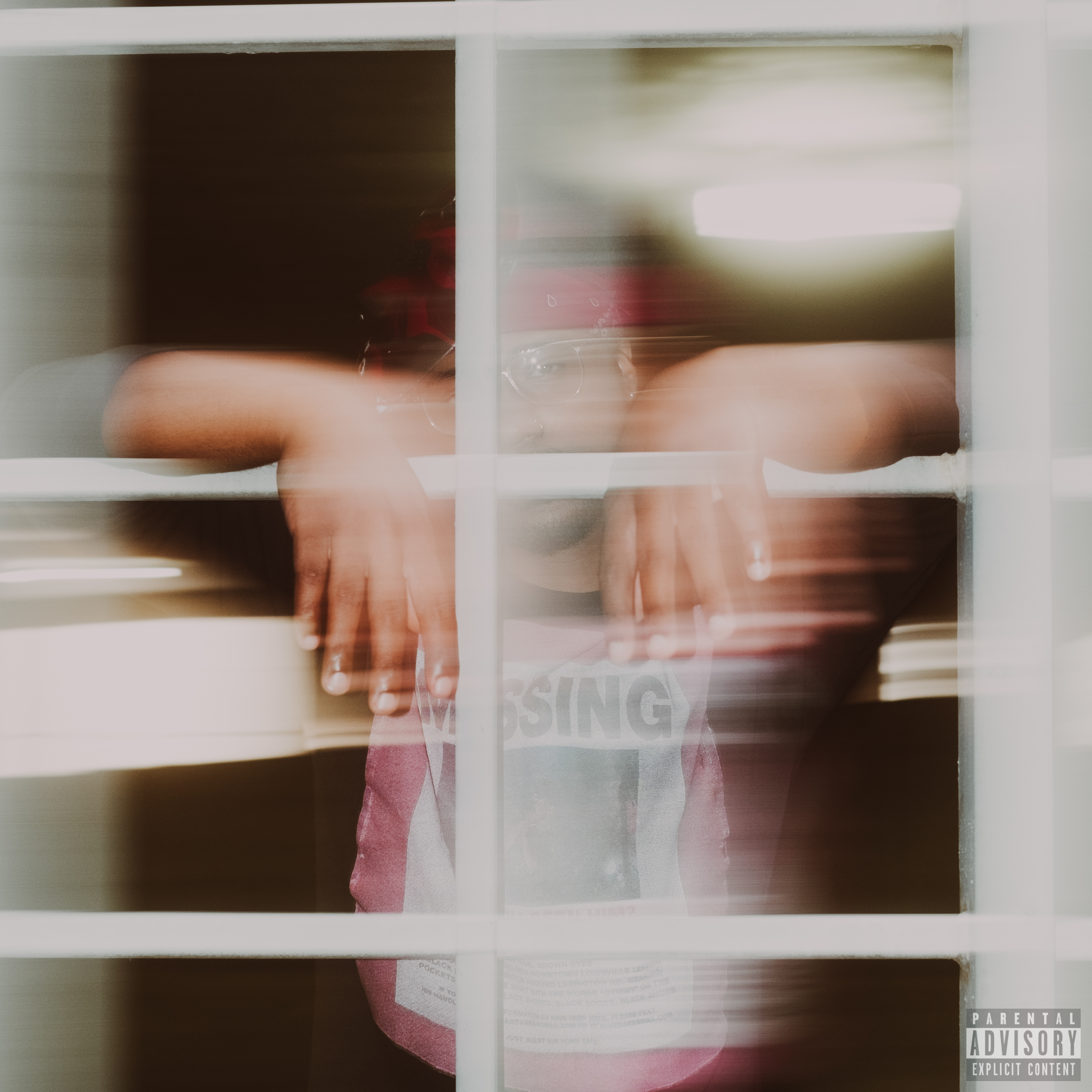 A reflective surface capturing a person's torso, hand, phone, and part of a sticker labeled 'PARENTAL EXPLICIT CONTENT' in the lower right corner.