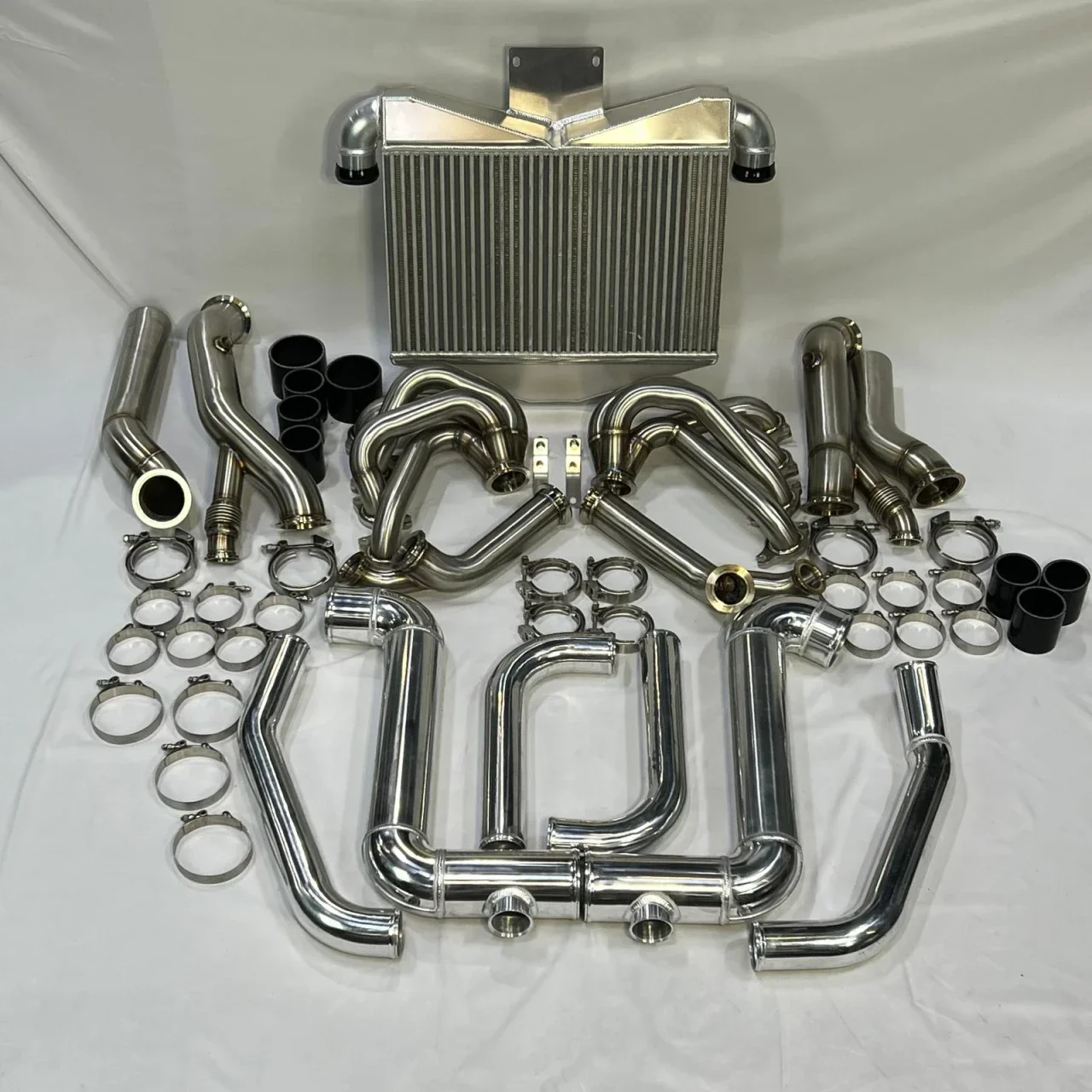 Arranged automotive intercooler parts including pipes, hoses, clamps, and a radiator.