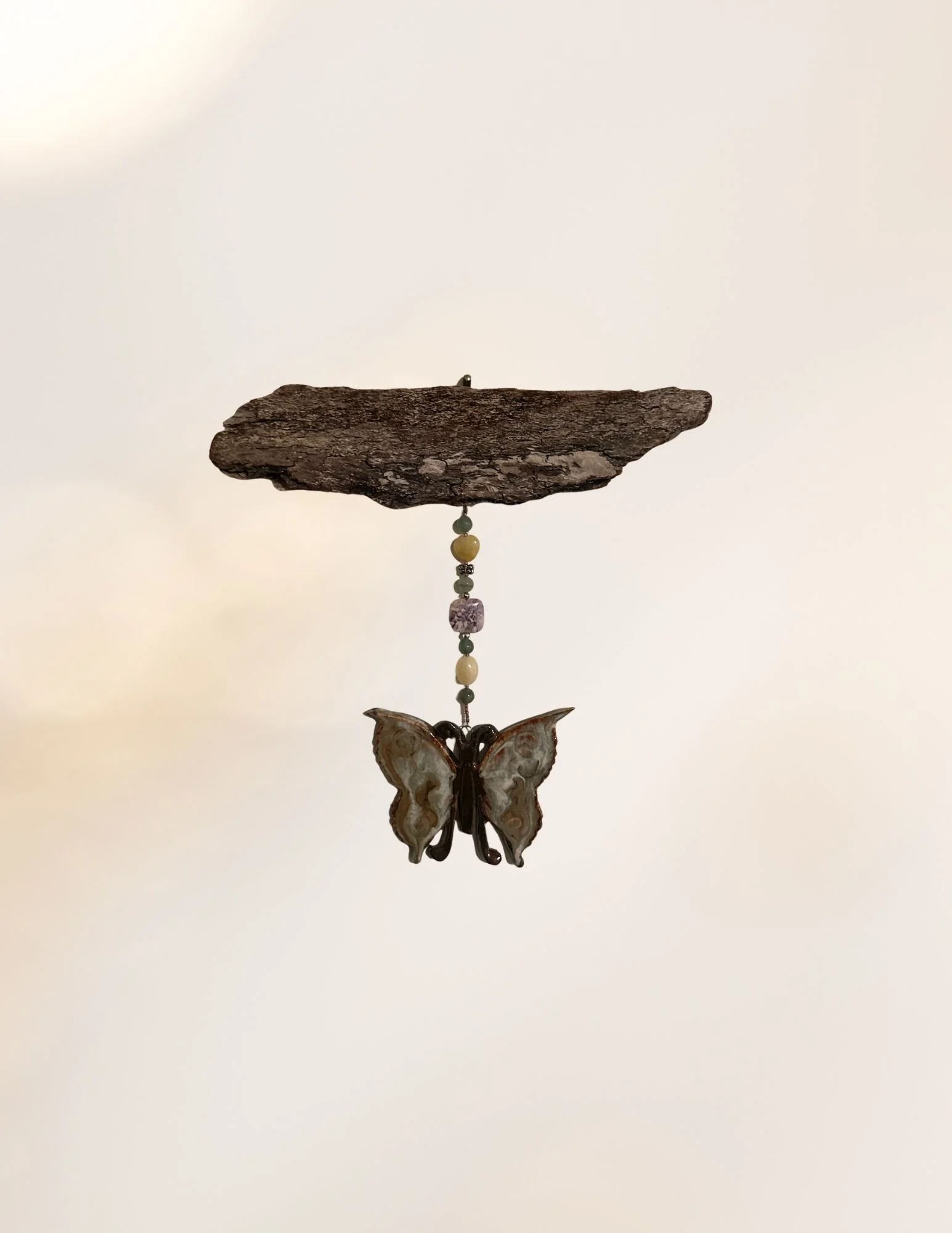 Decorative hanging ornament featuring a butterfly and beads against a plain background.