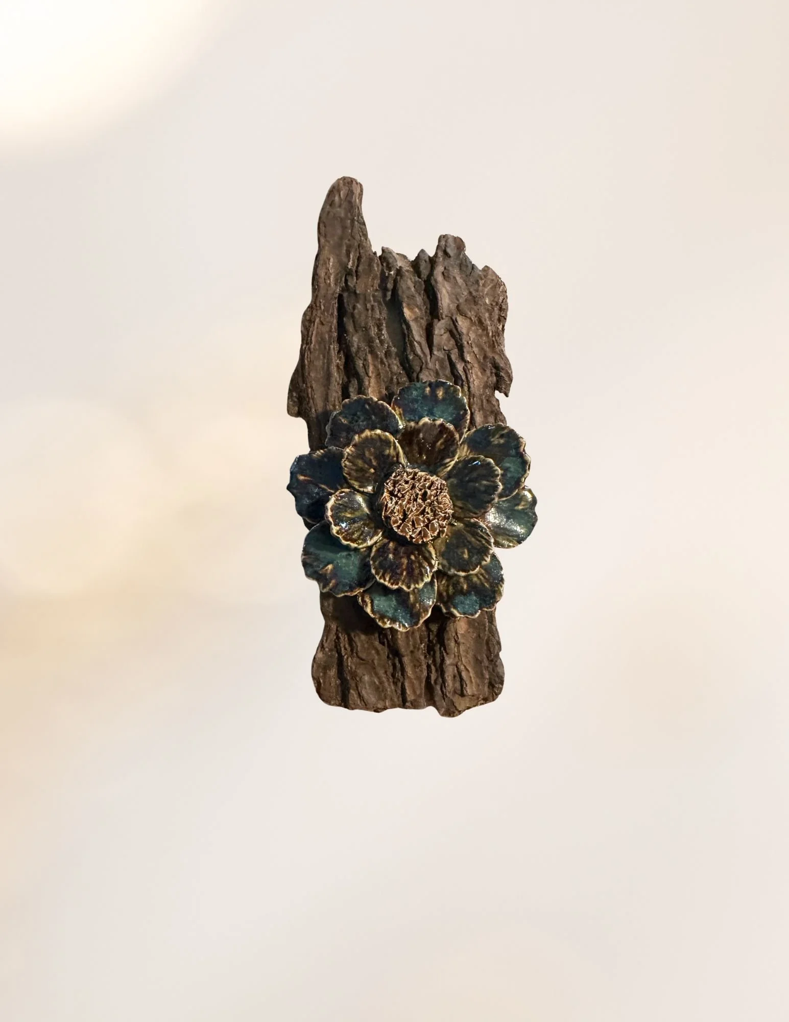 A decorative sculpture of a flower with dark petals and a textured brown center, mounted on a textured rock-like base.