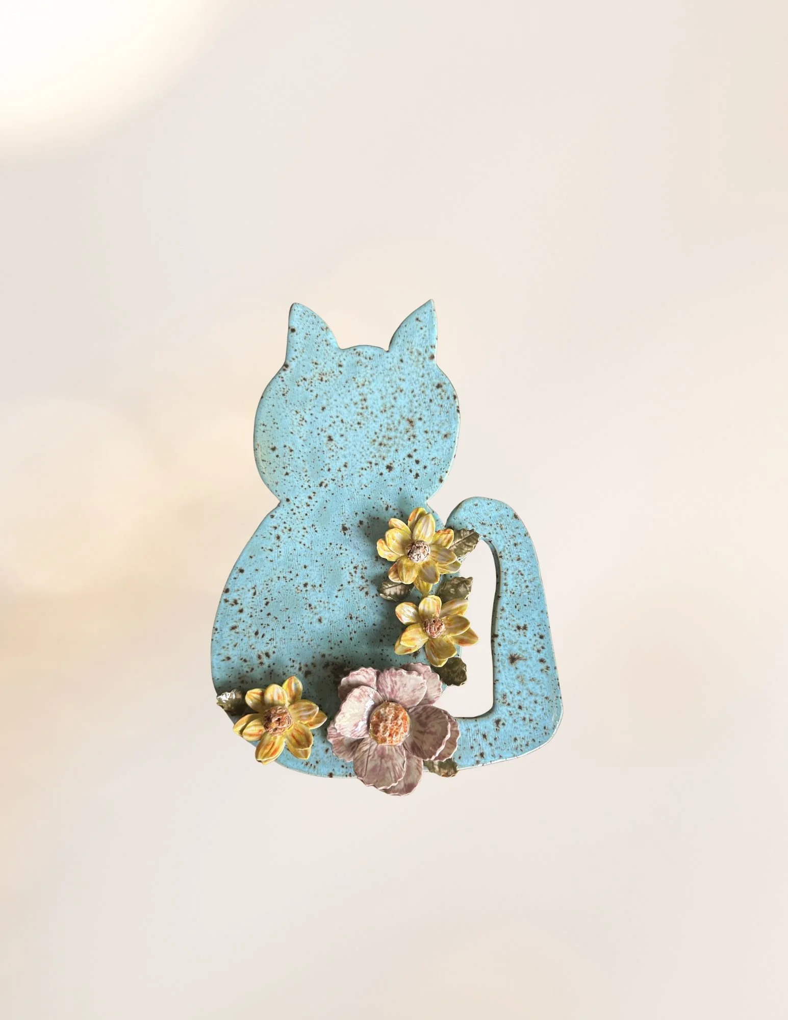 A blue, rusted metal silhouette of a cat with flowers attached at the base.