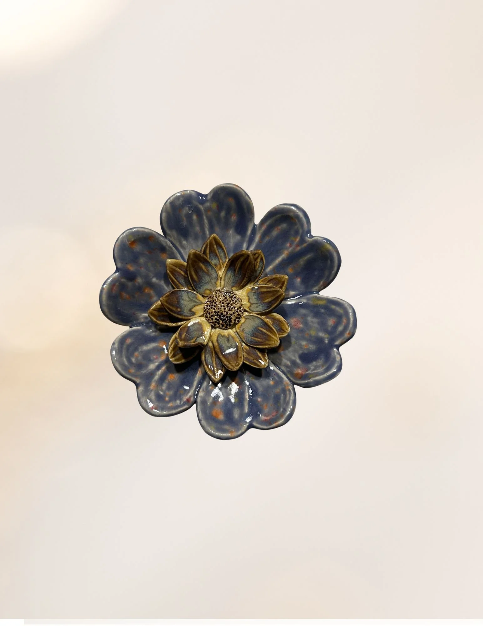 Ceramic flower-shaped dish with gold and brown accents on a white surface.