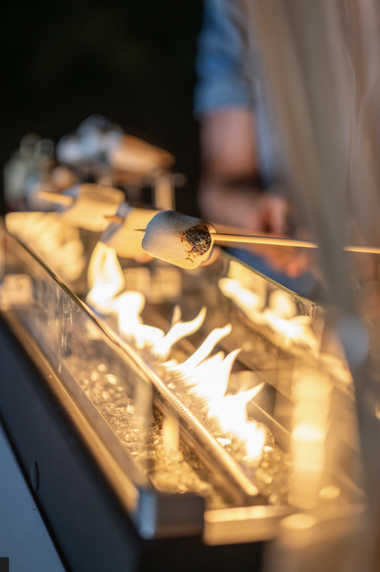 Marshmallows being roasted over an open flame at a fire pit or grill.