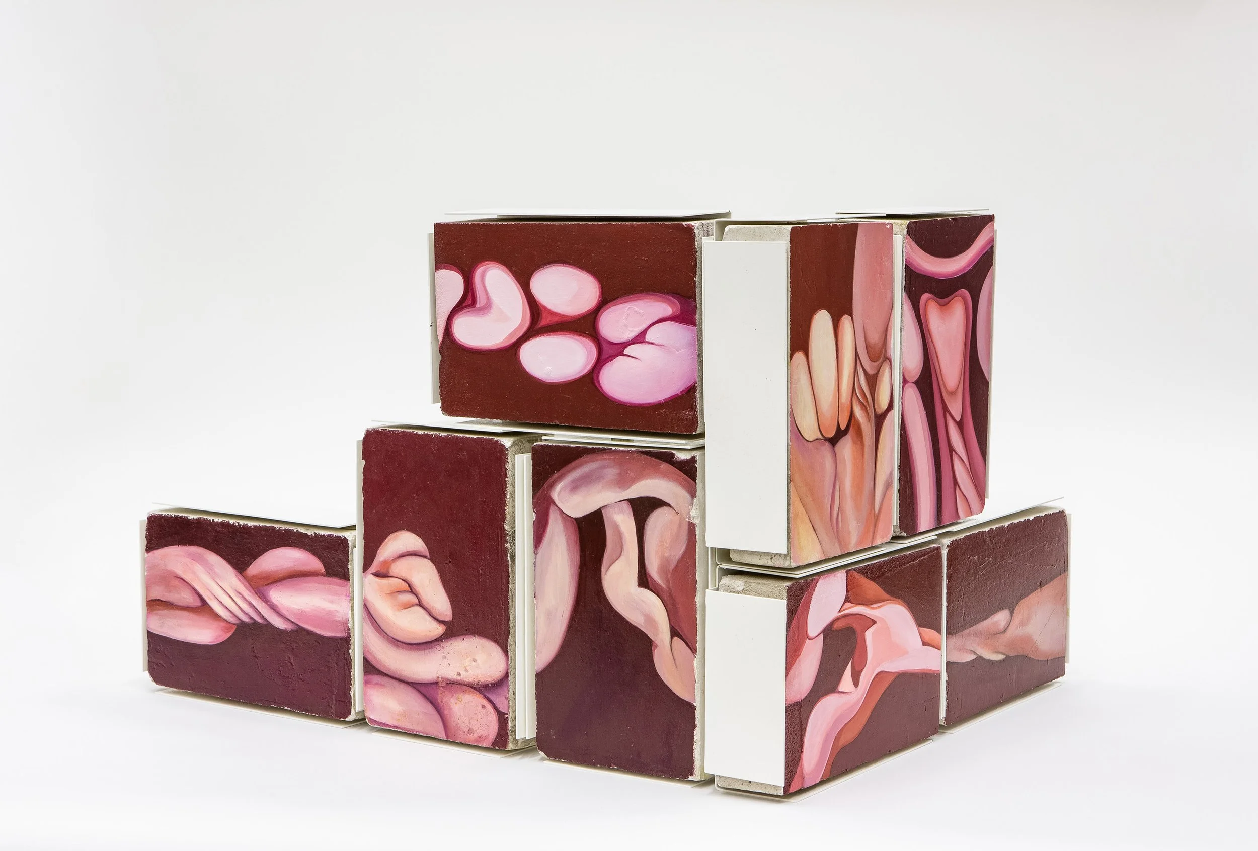 Conjunto de bloques de cerámica con patrones abstractos en tonos rosa, beige y marrón, apilados de manera artística sobre fondo blanco.