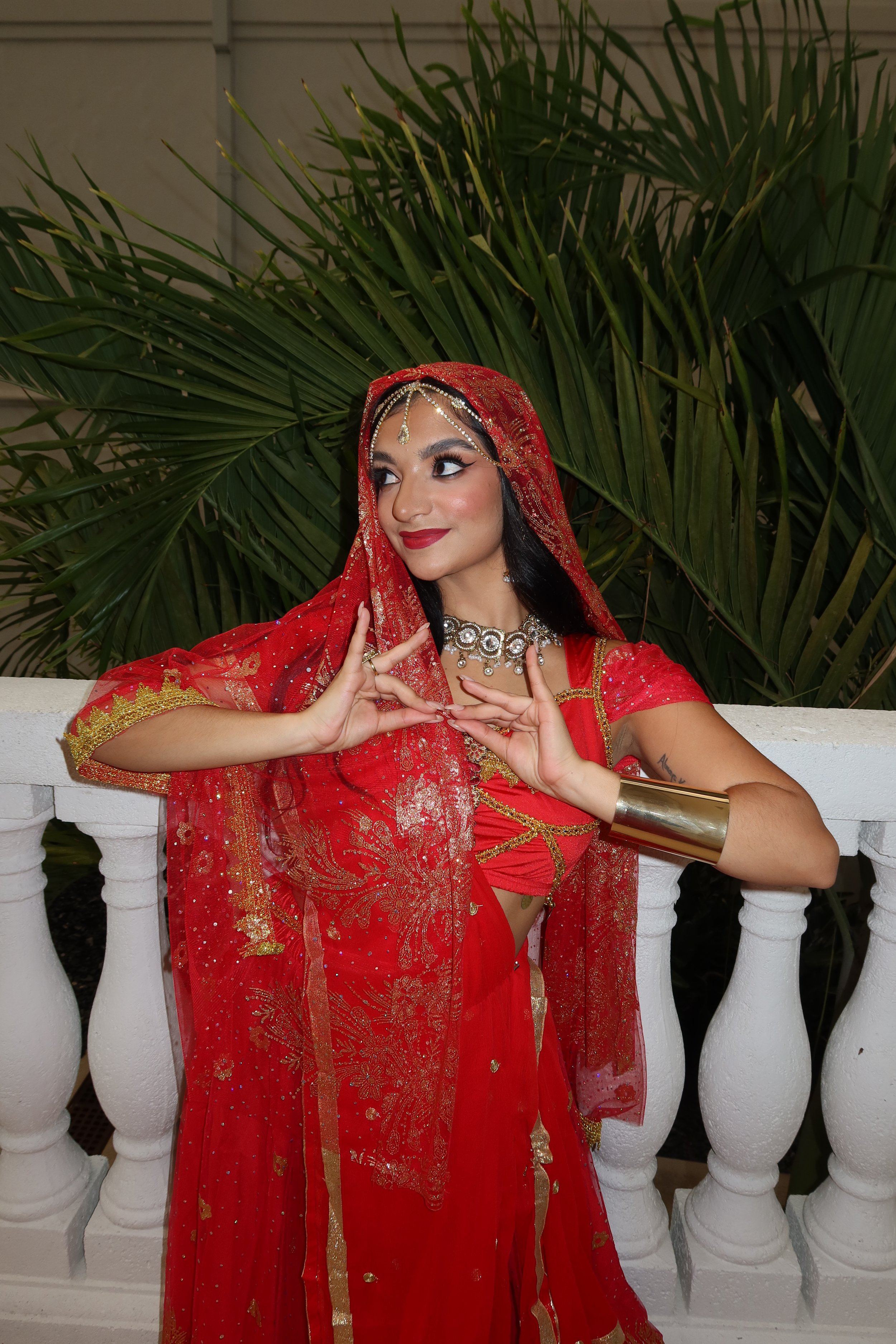 Isabella Damiani wearing a traditional Indian saree with gold detailing, jewelry, and a red veil.