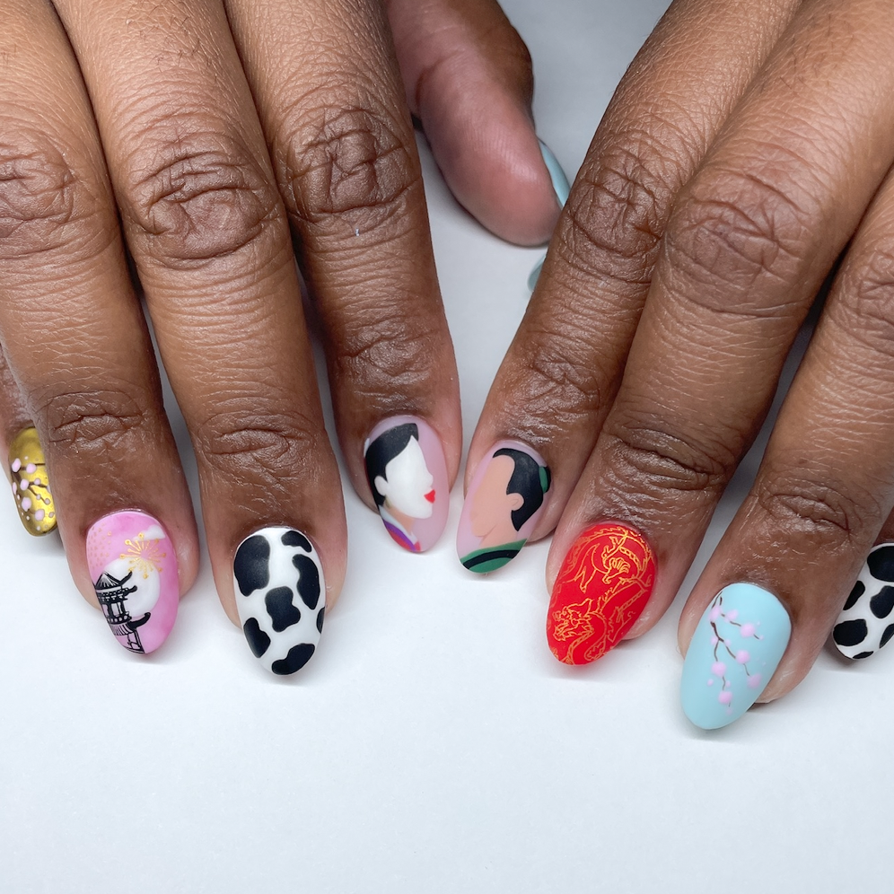 Close-up of hands with colorful, artistically designed nails featuring various cultural and nature-inspired patterns.