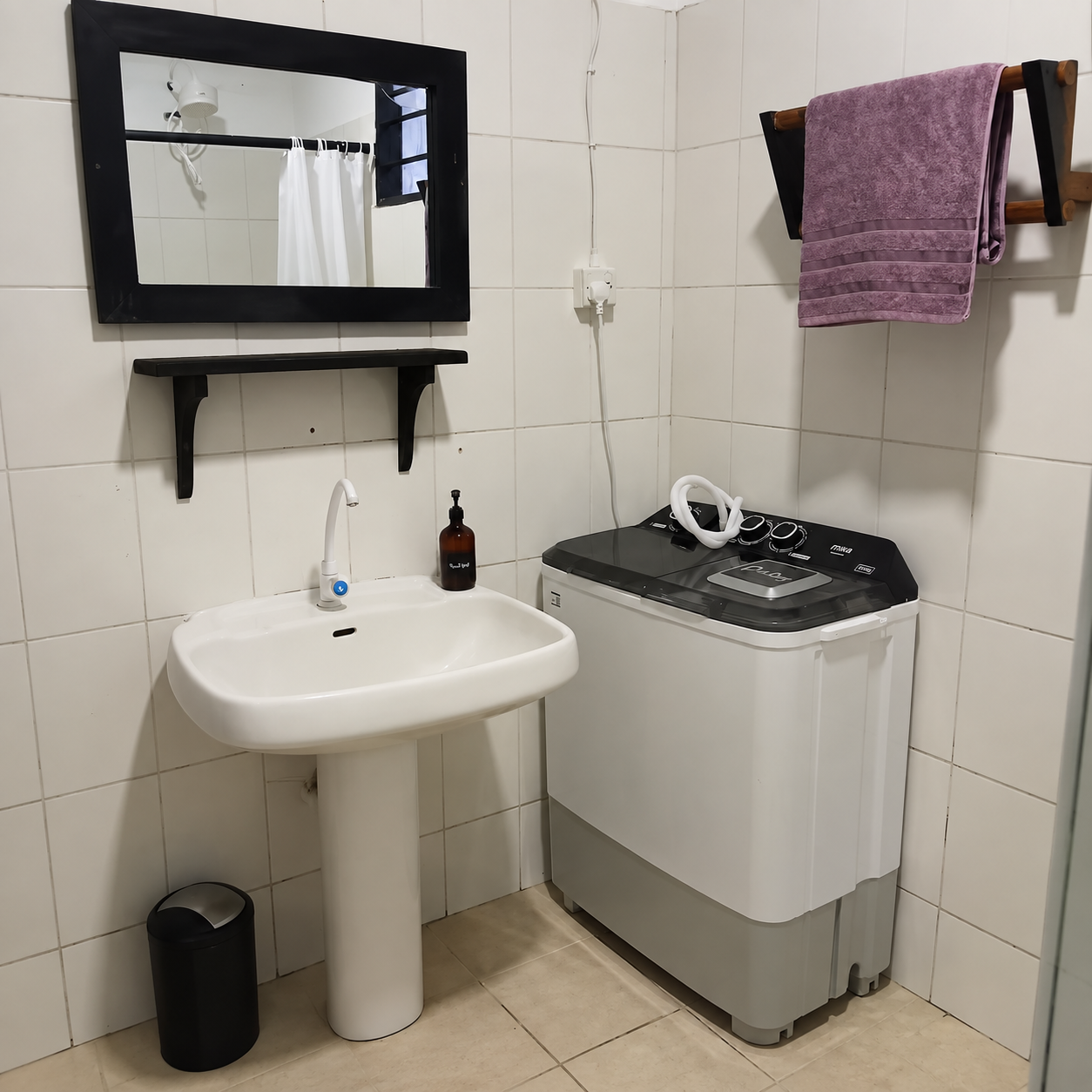 Private bathroom with sink and washing machine at The Suites in Diani Beach.