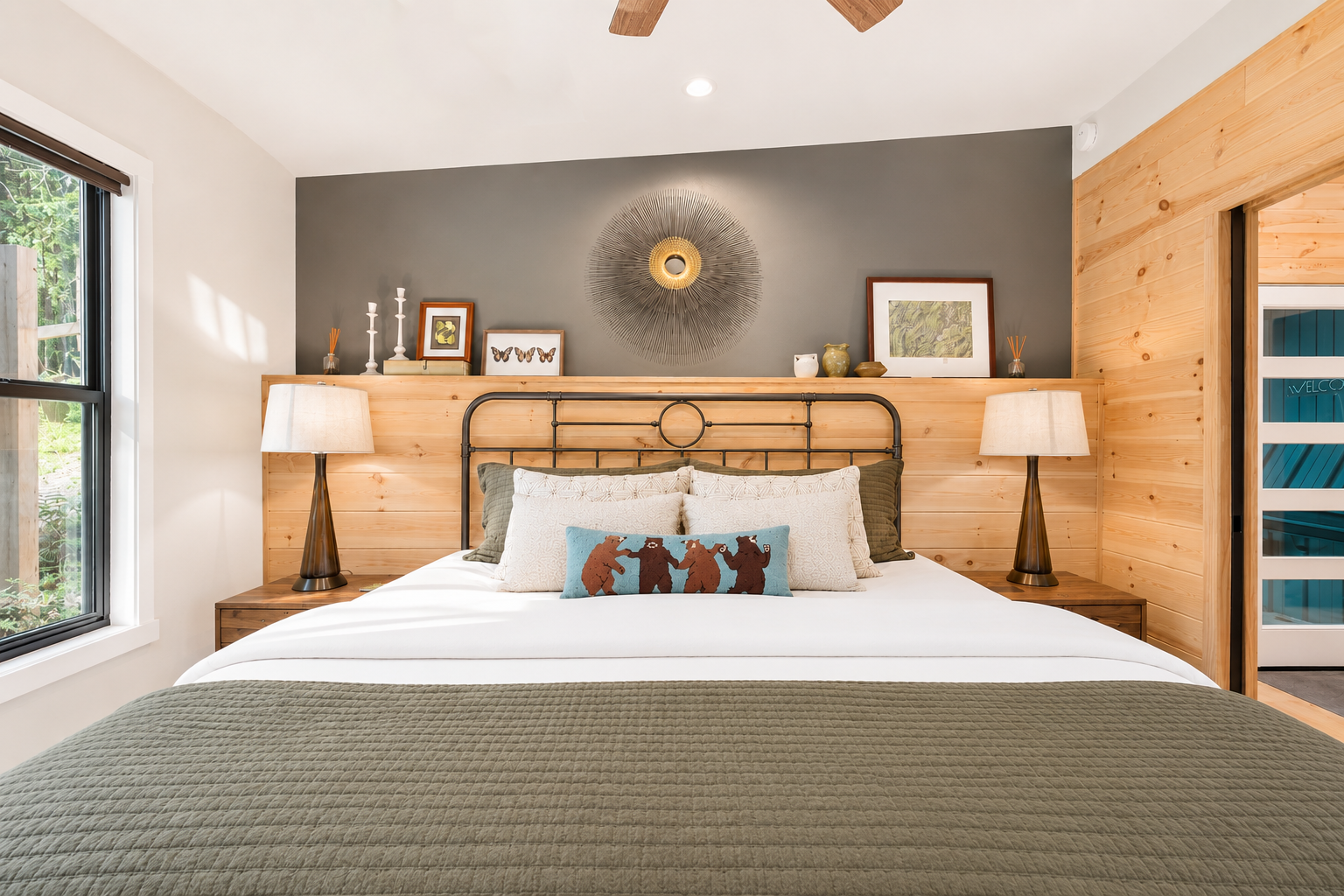 A cozy bedroom with a bed, two nightstands with lamps, and decor on a wood-paneled wall, including framed pictures and a wall sculpture.