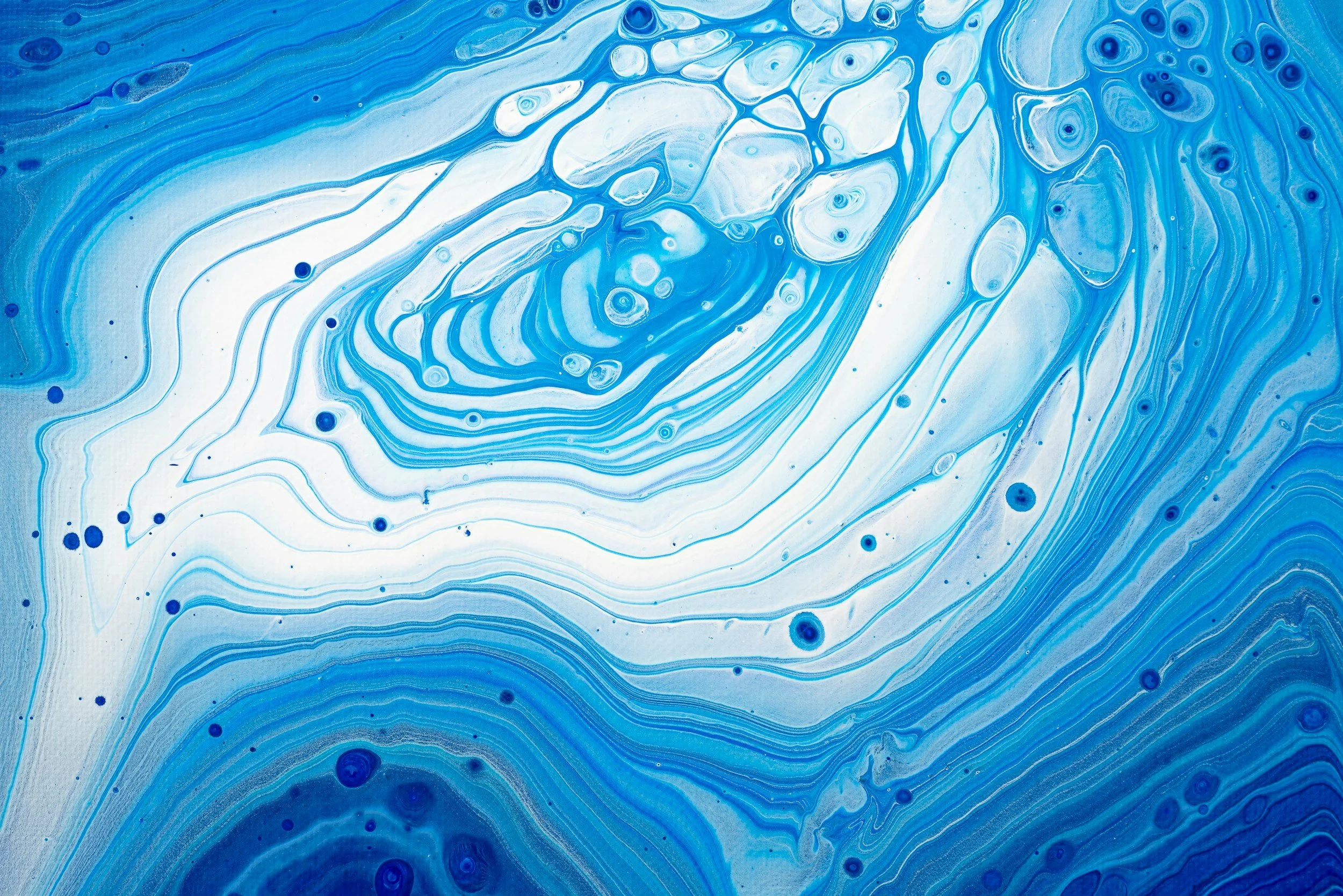Blue and white abstract marbled pattern with swirls and small dots. Acrylic pour painting.
