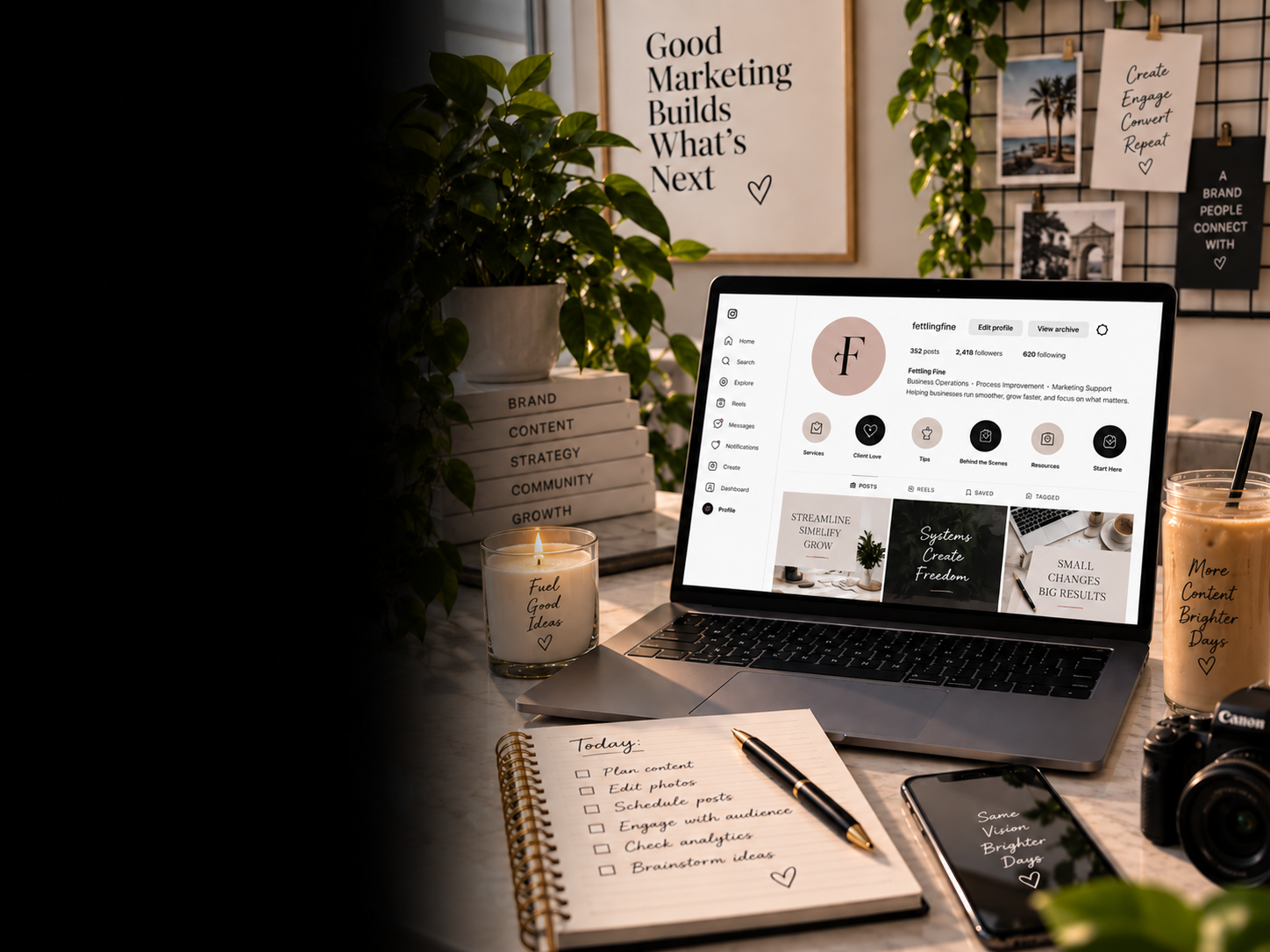 An organized workspace with a laptop displaying an Instagram profile, a candle with the phrase "Fuel Good Ideas," a notebook with a to-do list, a camera, and a smoothie cup, with decorative plants and motivational posters in the background.