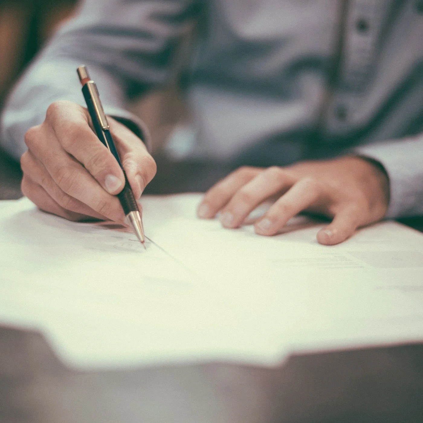 Close-up of a person writing on paper with a black and gold pen
