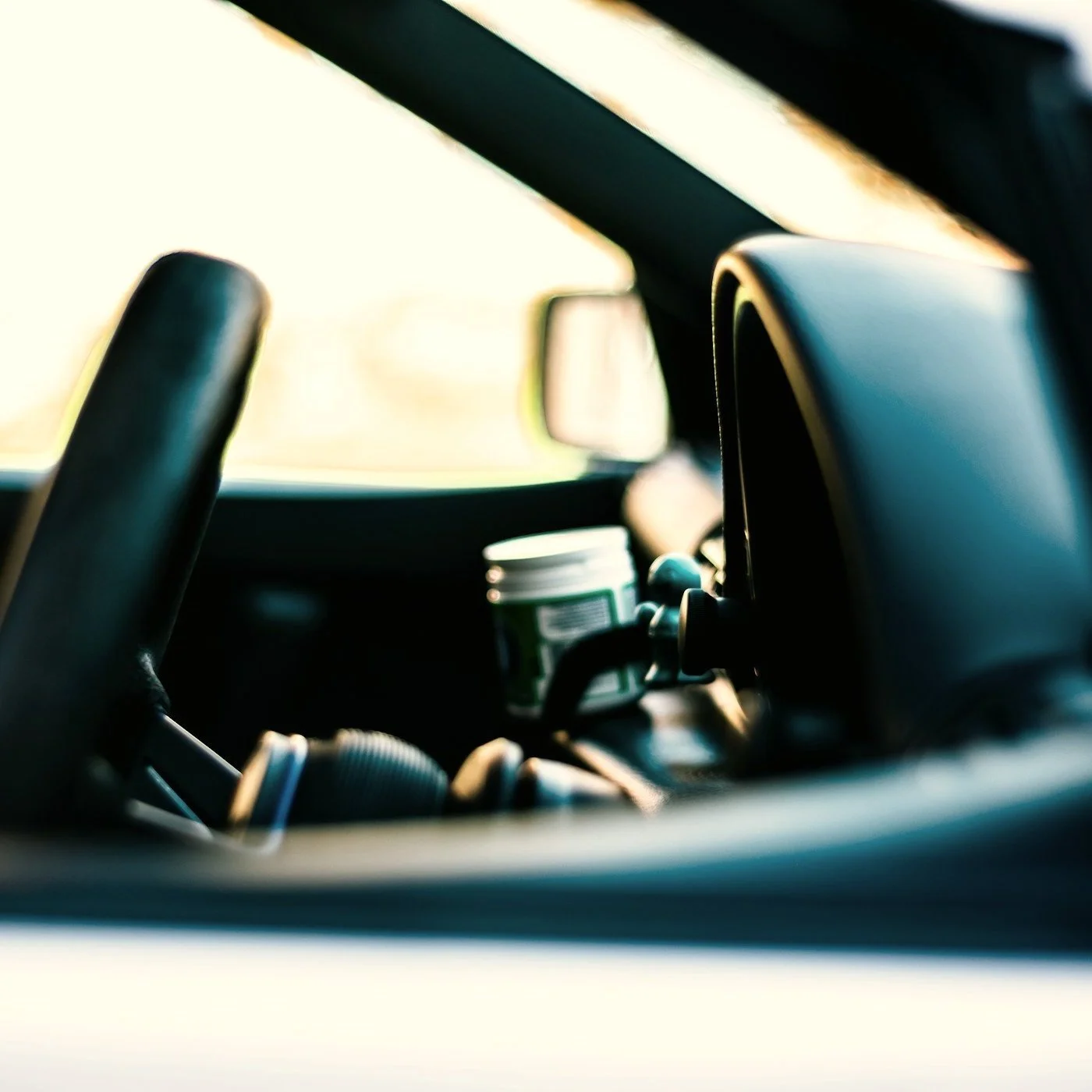 Close-up view of a car interior showing the steering wheel, dashboard, side mirror, and front seat.