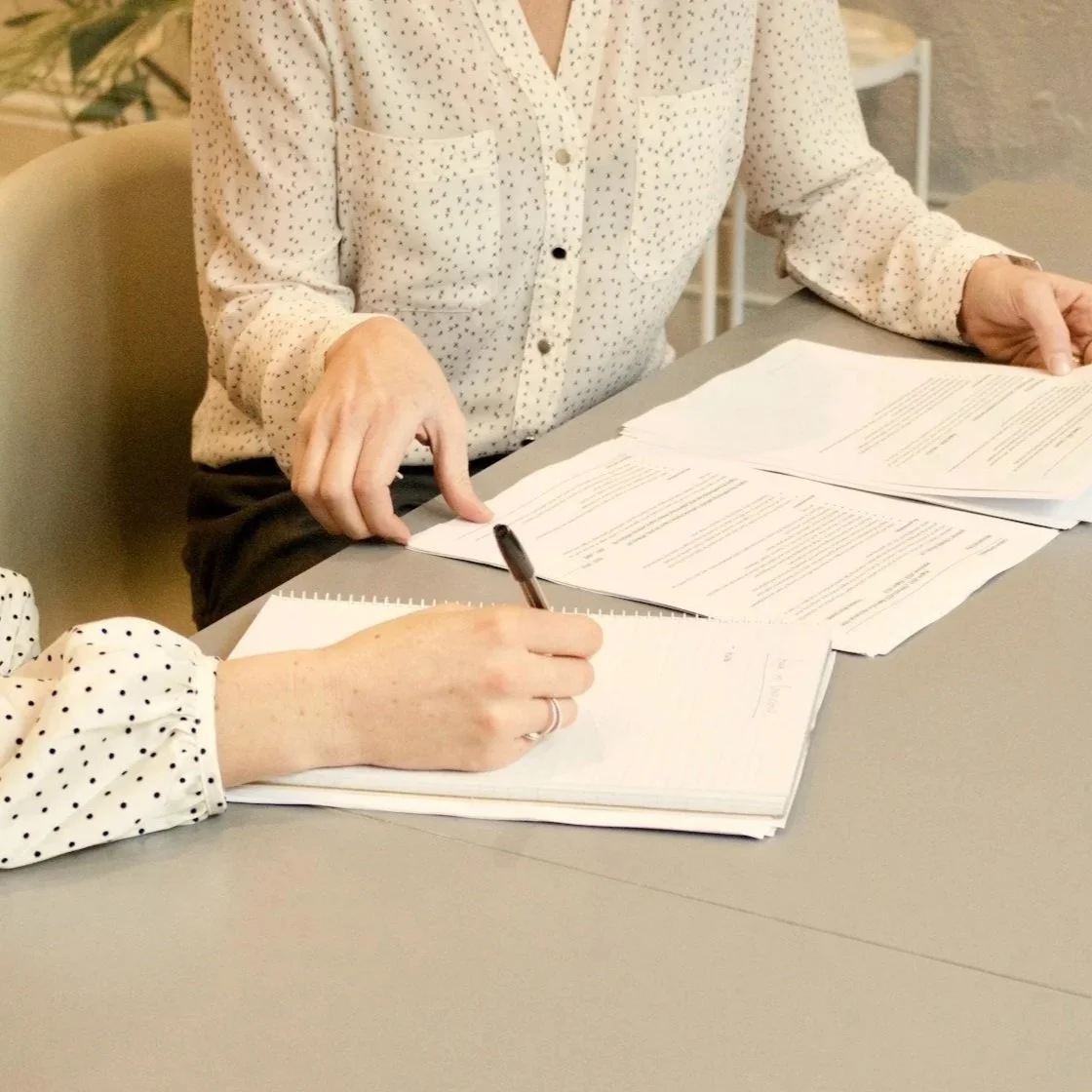 Two people reviewing and signing documents at a table