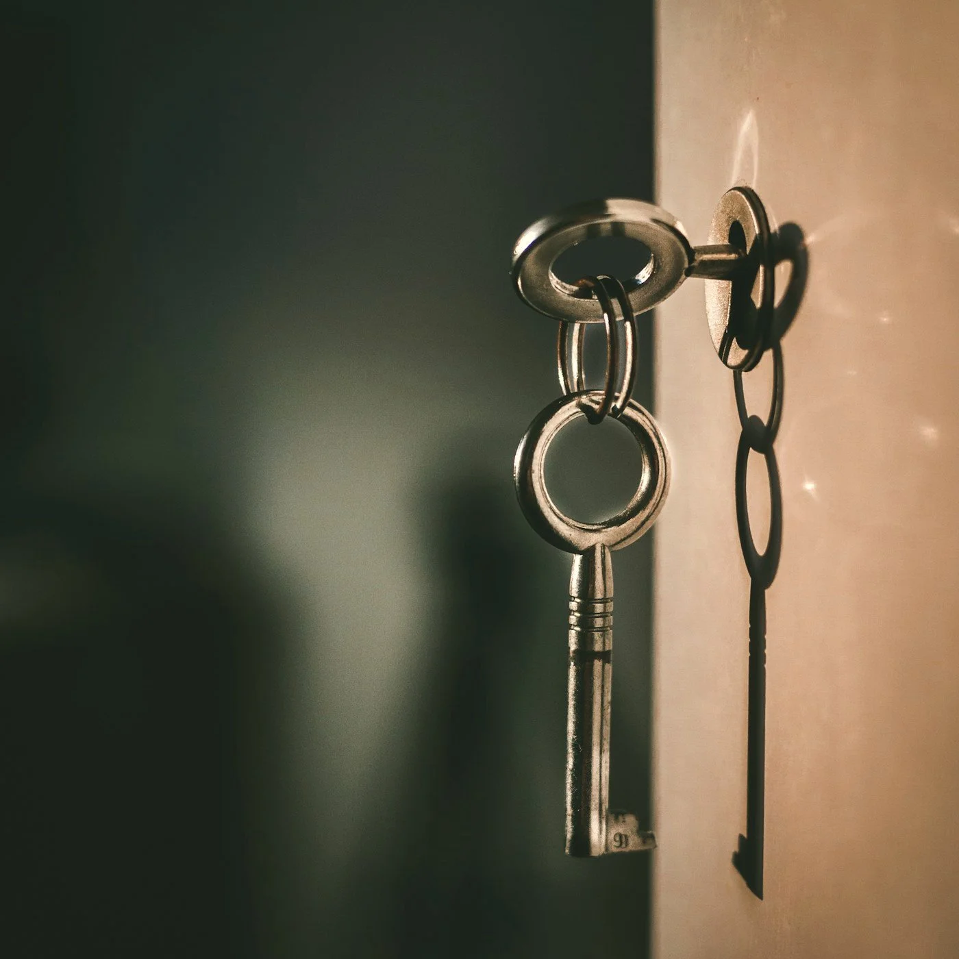 Vintage metal key hanging from an antique keyhole in warm light
