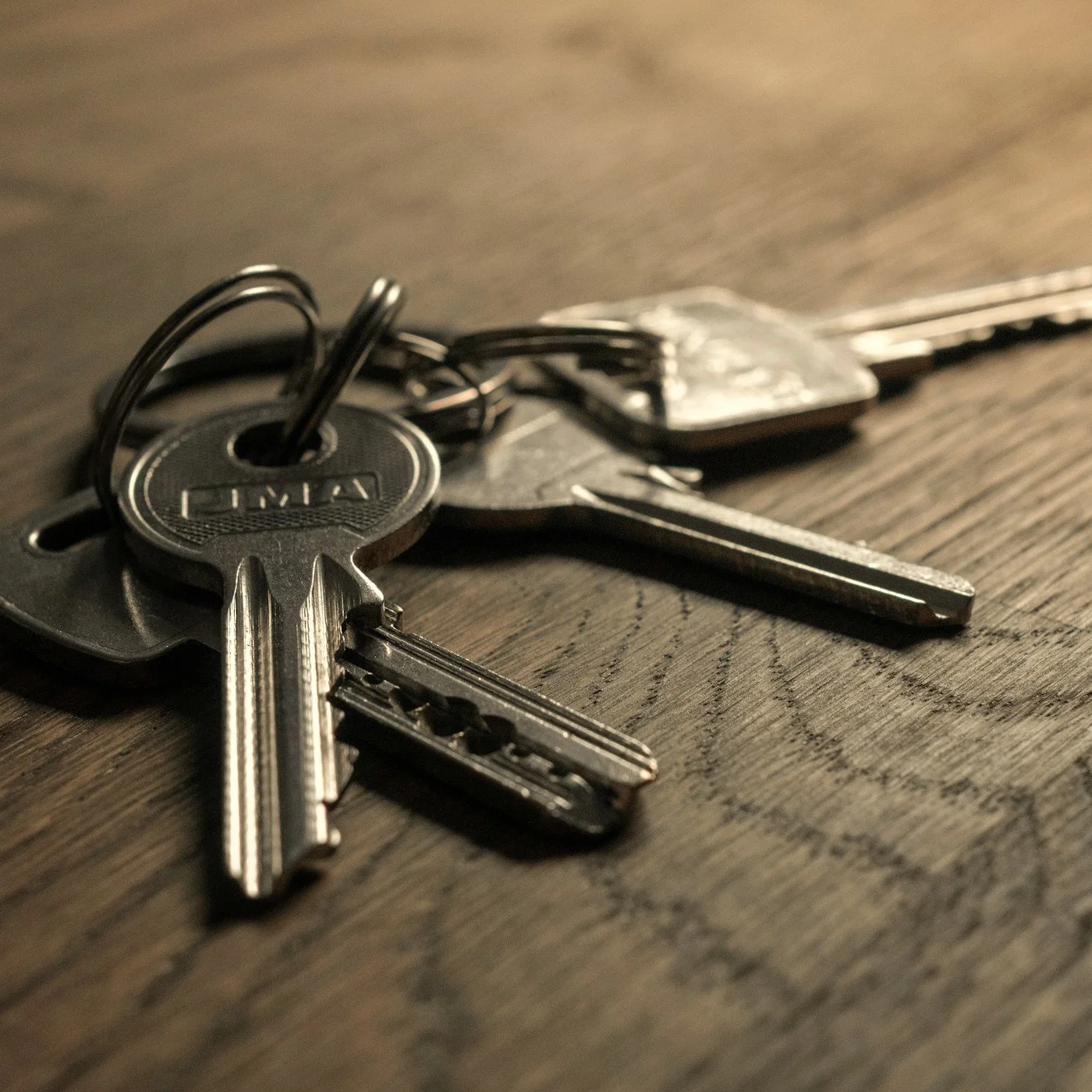 Close-up of several metal keys on a key ring resting on a wooden table
