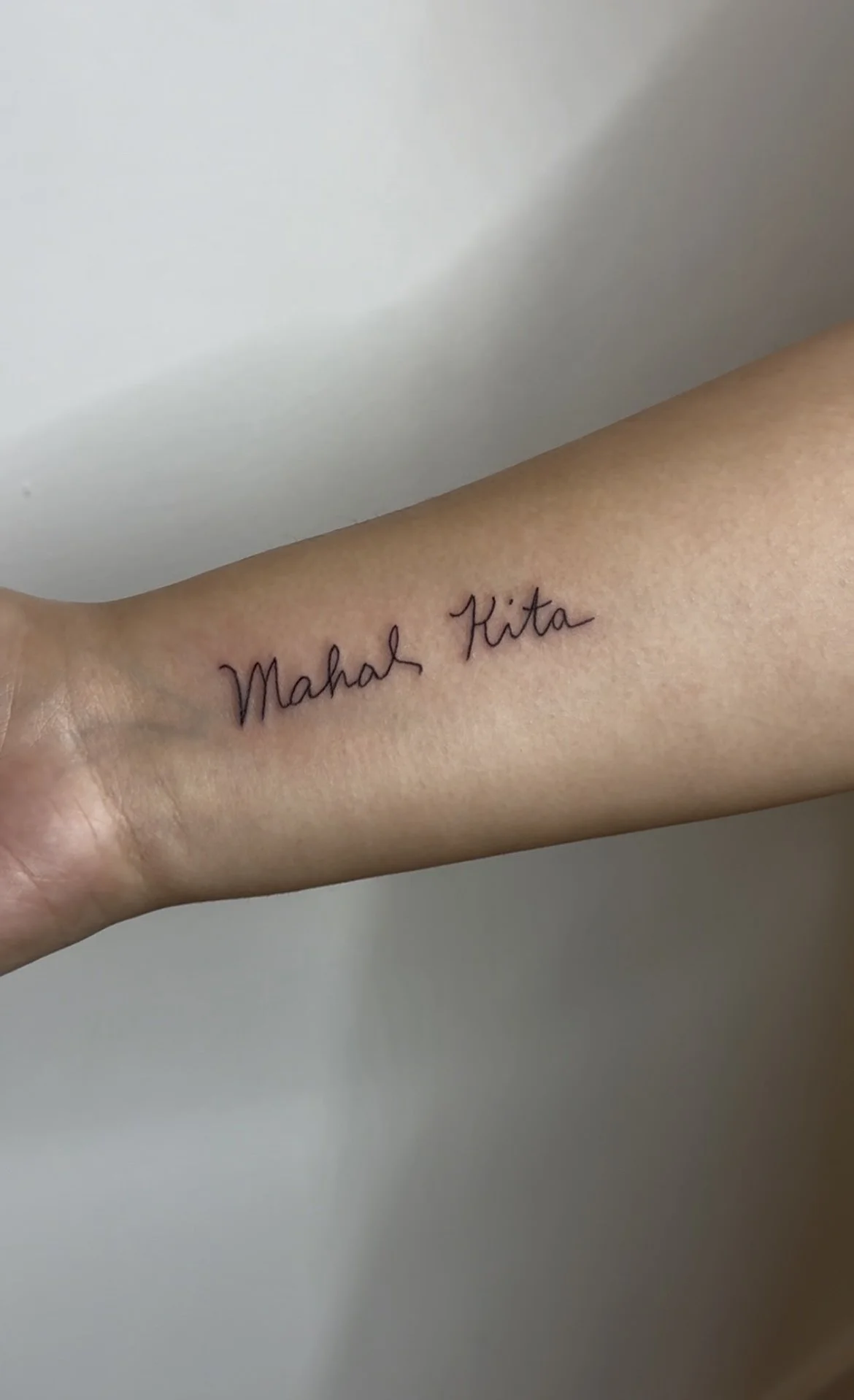 Tattoo on inner forearm with the words 'Mahal Kita' written in cursive black ink.