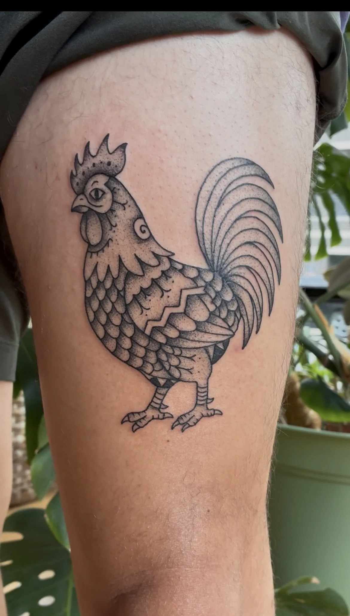 Black line tattoo of a rooster on person's upper arm.