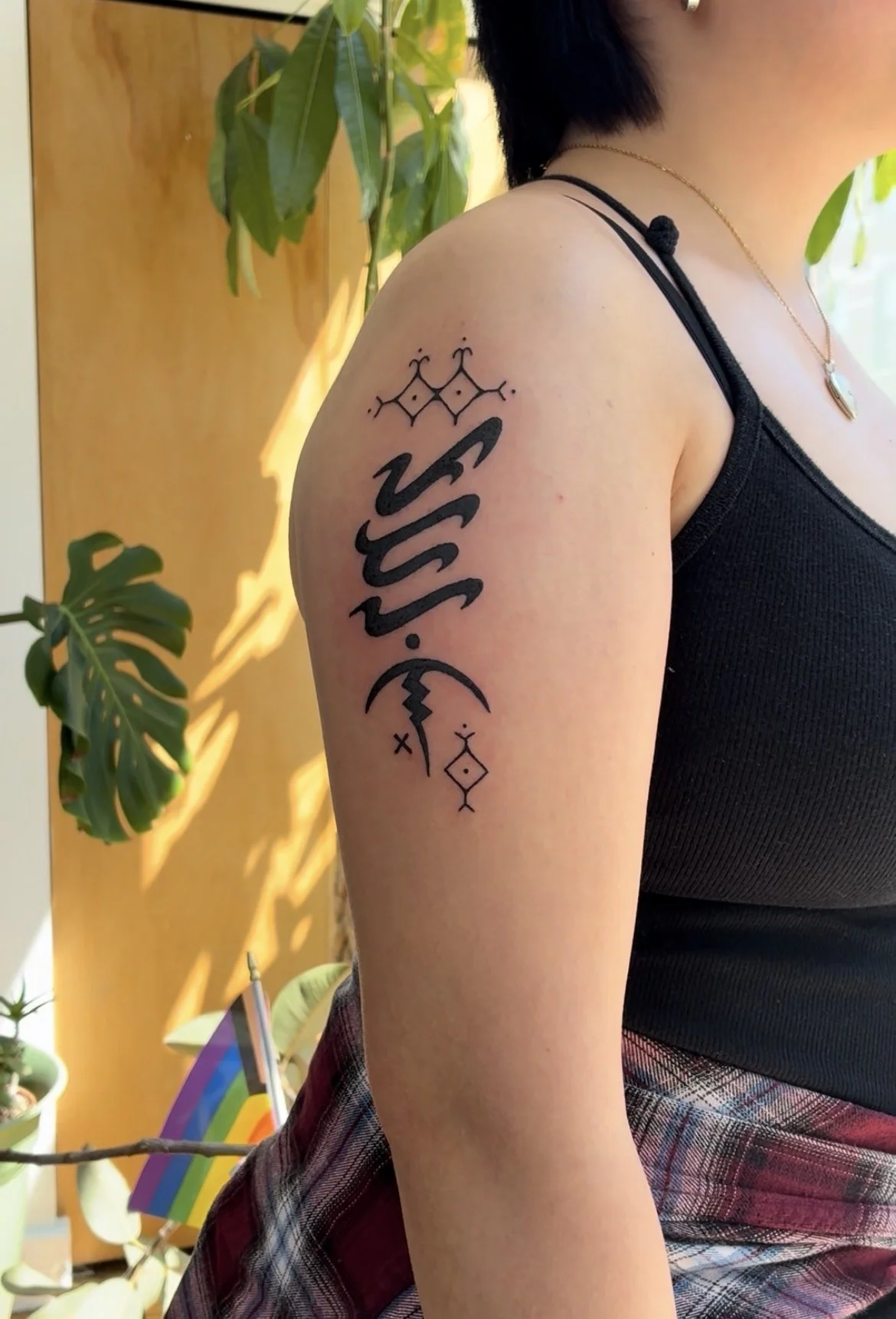 Tattoo on person's upper arm featuring geometric and symbolic designs.