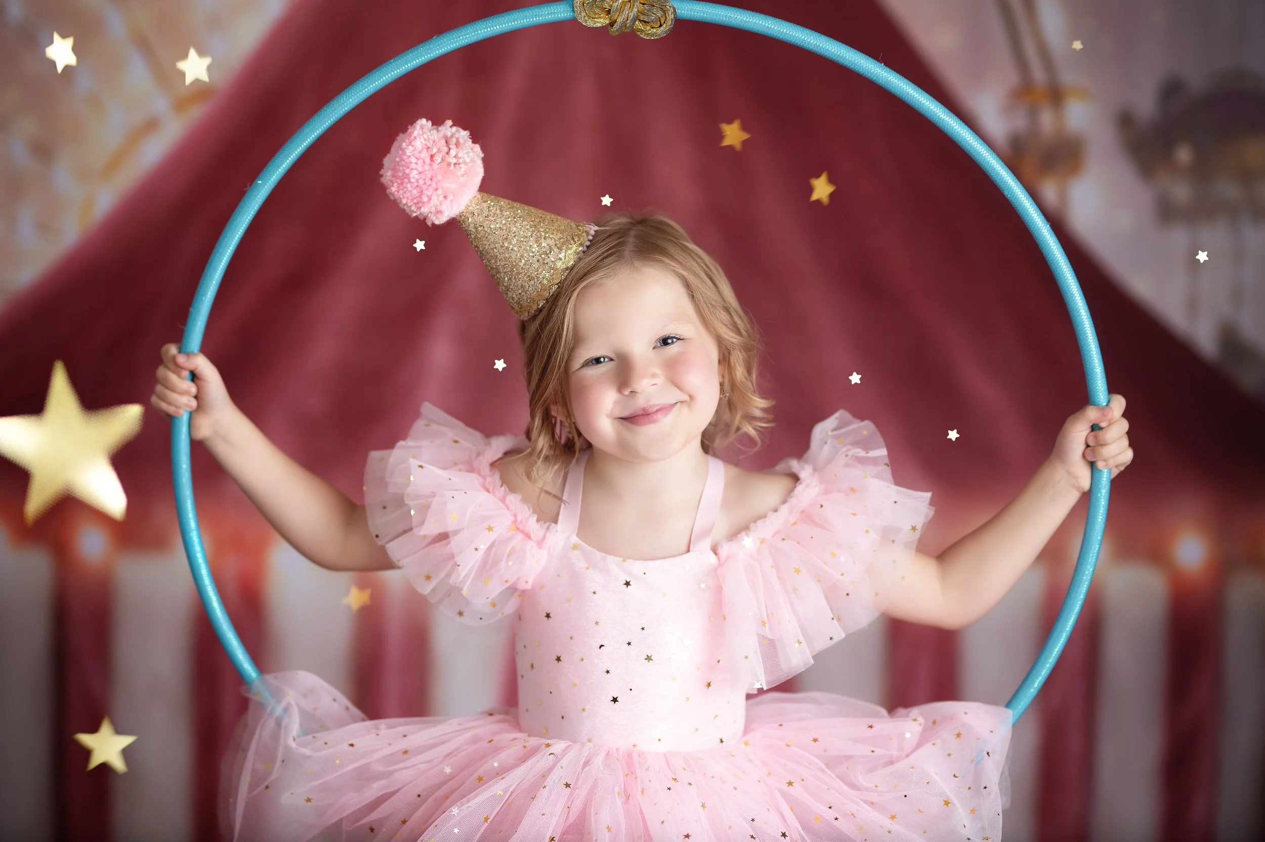Young girl posing inside a hoop during a colorful circus-themed birthday photography session.