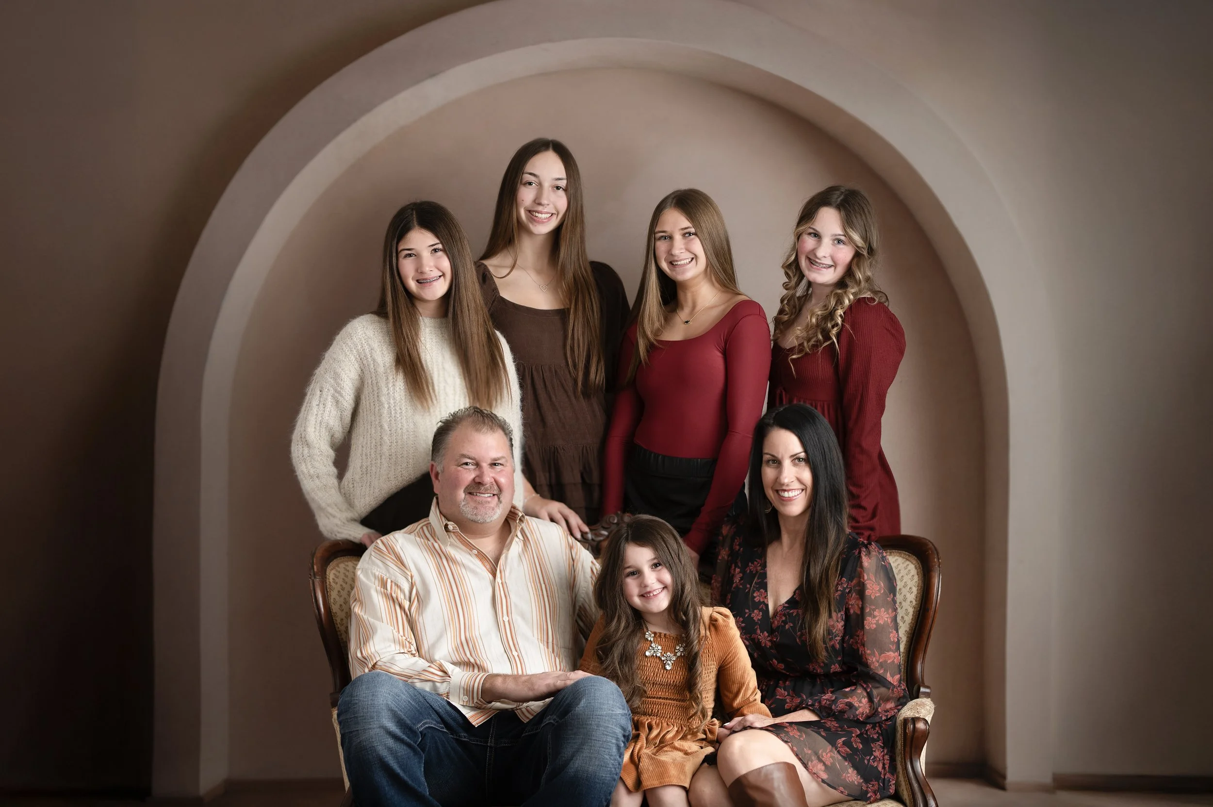 Family posing together during a warm neutral studio portrait session.