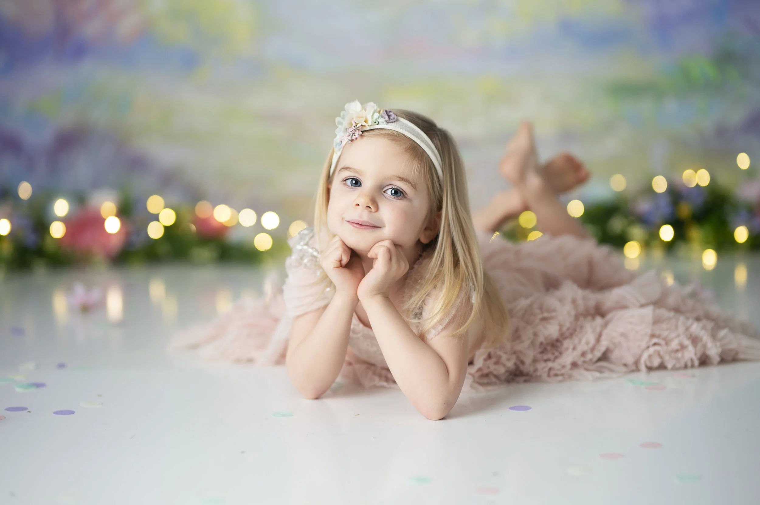 Young girl lying on the floor and smiling during a pastel rainbow photography session.