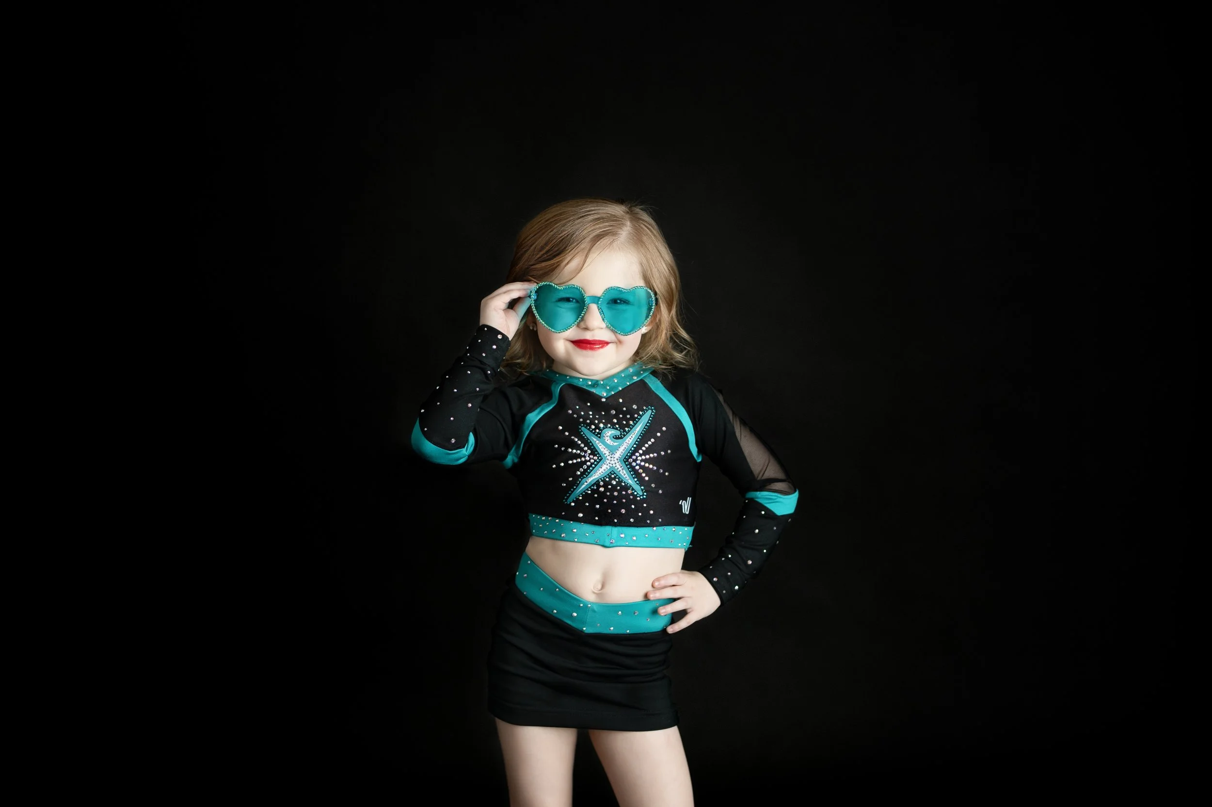 Young cheer athlete posing in uniform during a studio sports portrait session.