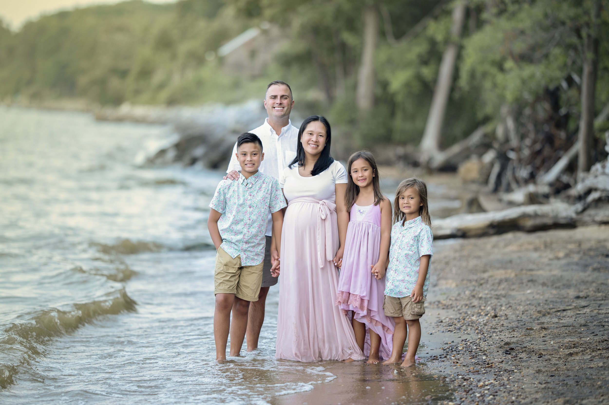 Expecting mother with her family standing along the water during a maternity photography session.