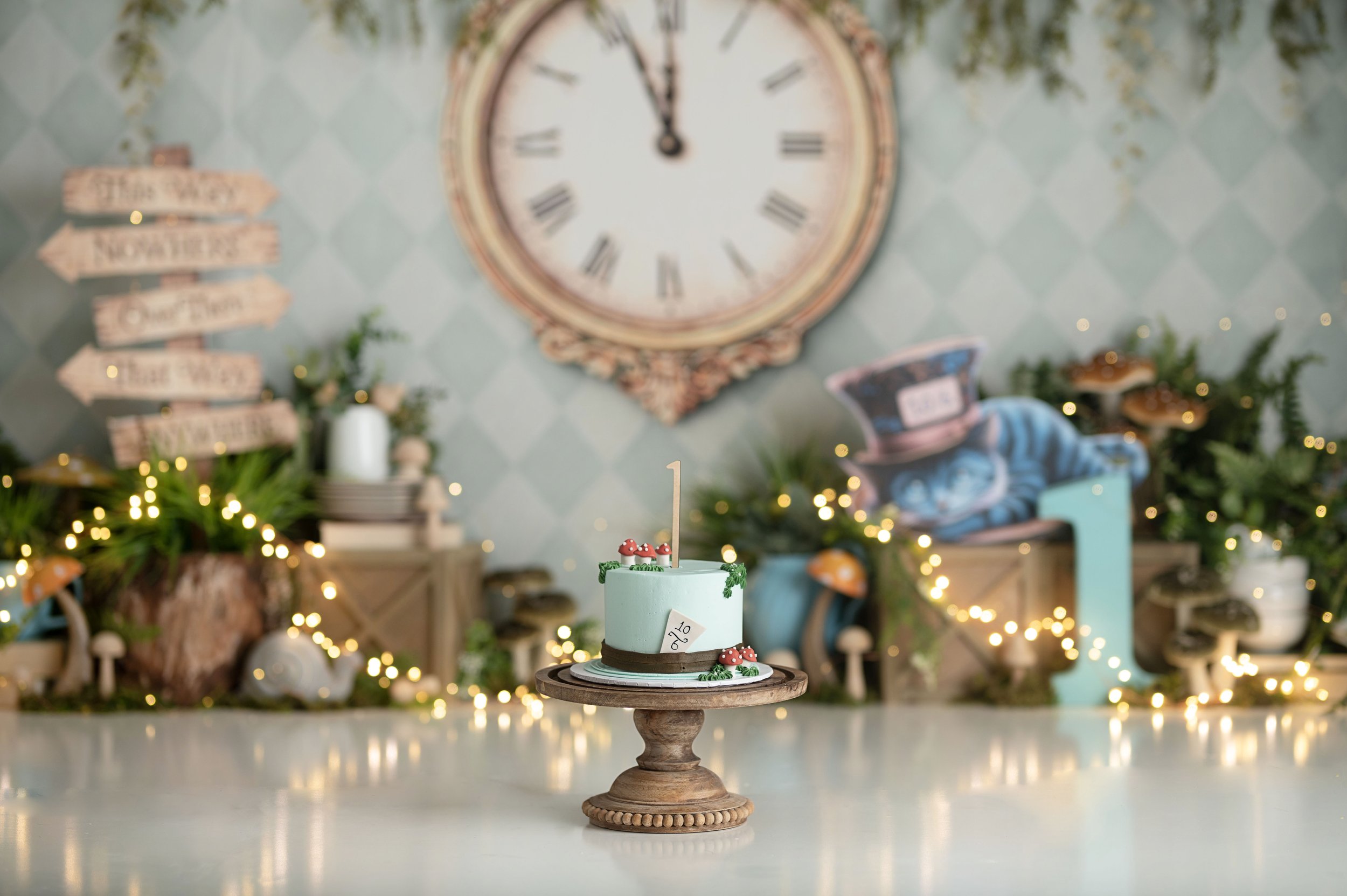 Wonderland-inspired Cake Smash set featuring a vintage clock, whimsical props, greenery, and a birthday cake.