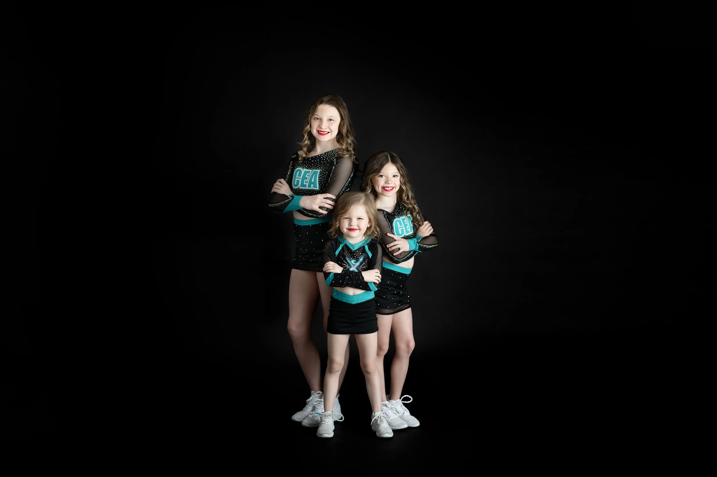 Three cheer athletes posing together during a studio sports photography session.