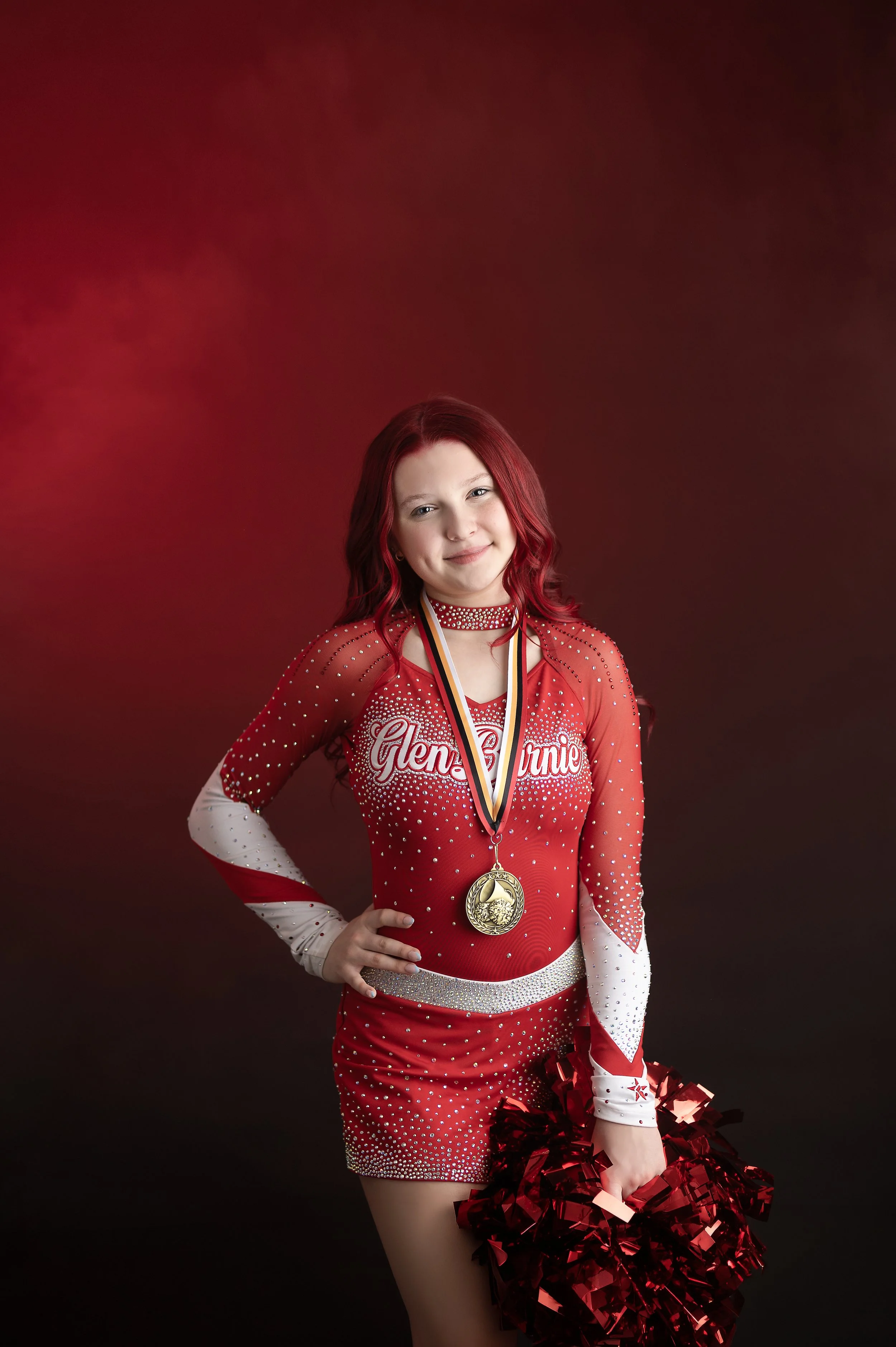 Cheer athlete in a red uniform photographed with dramatic red smoke effects.