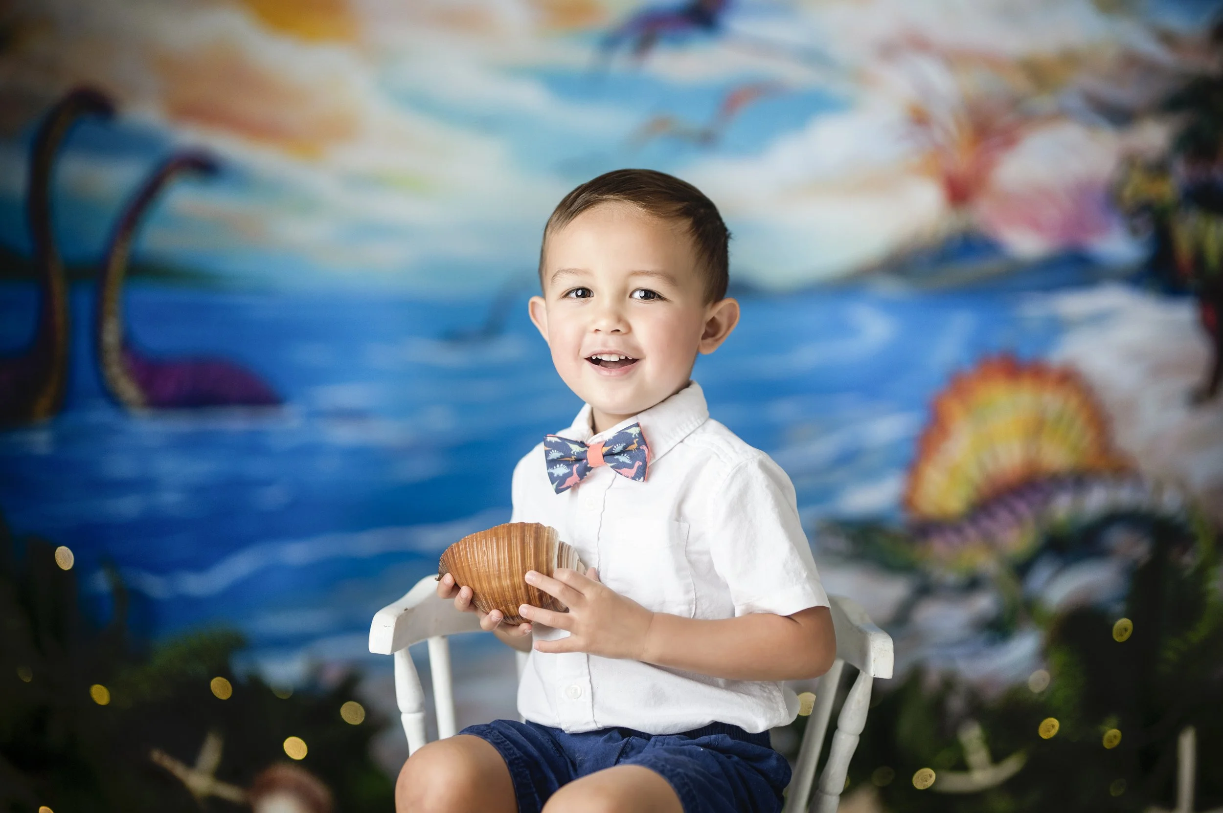 Smiling young boy dressed in a bow tie during a colorful milestone photography session.