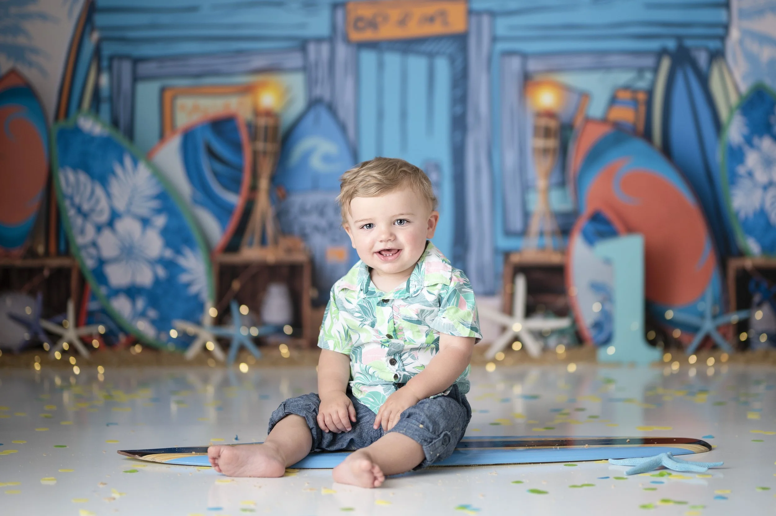 Baby boy sitting in a colorful surf-themed first birthday Cake Smash photography set.