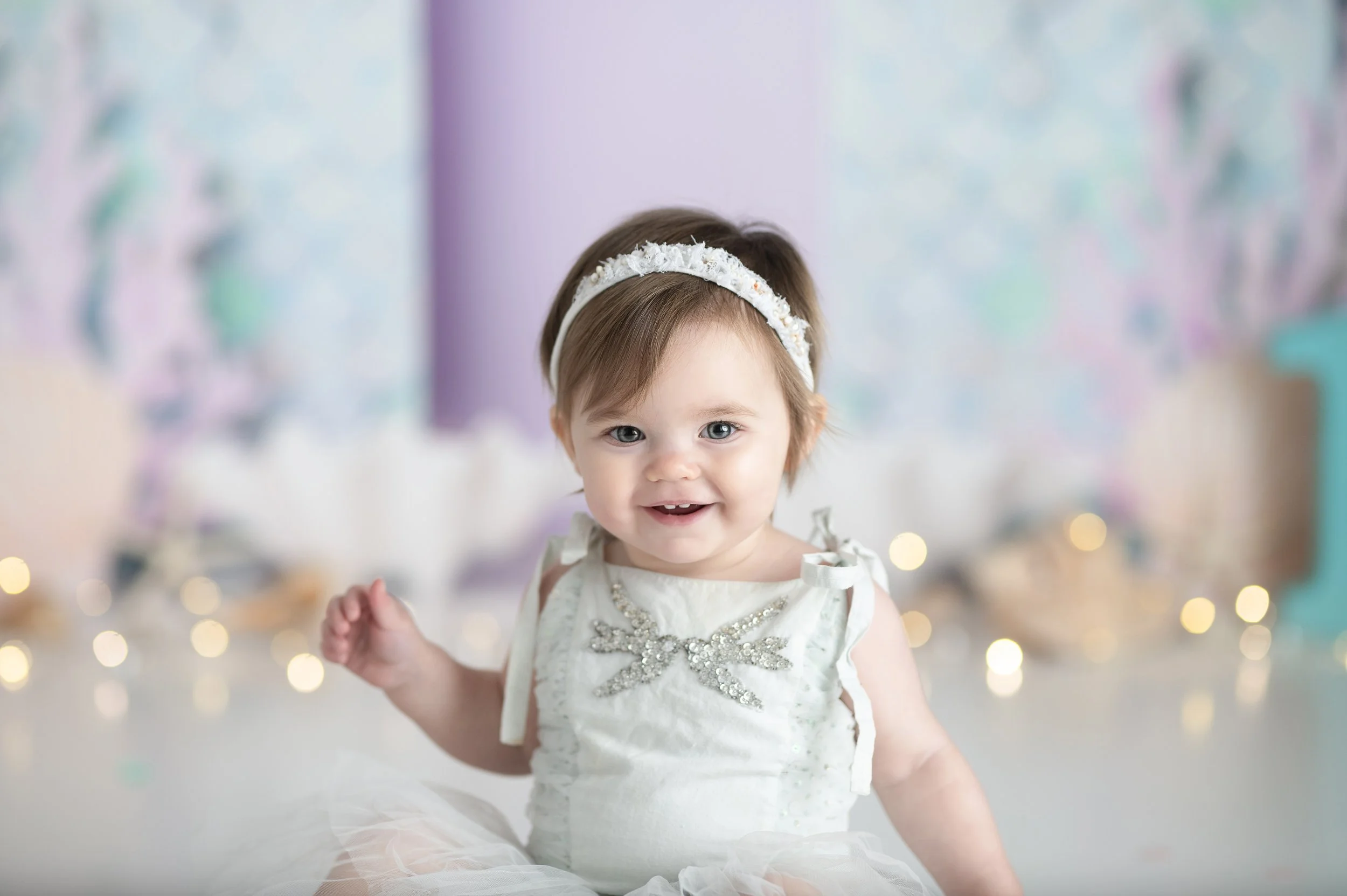 Young girl wearing a unicorn dress in front of a pastel rainbow photography backdrop.